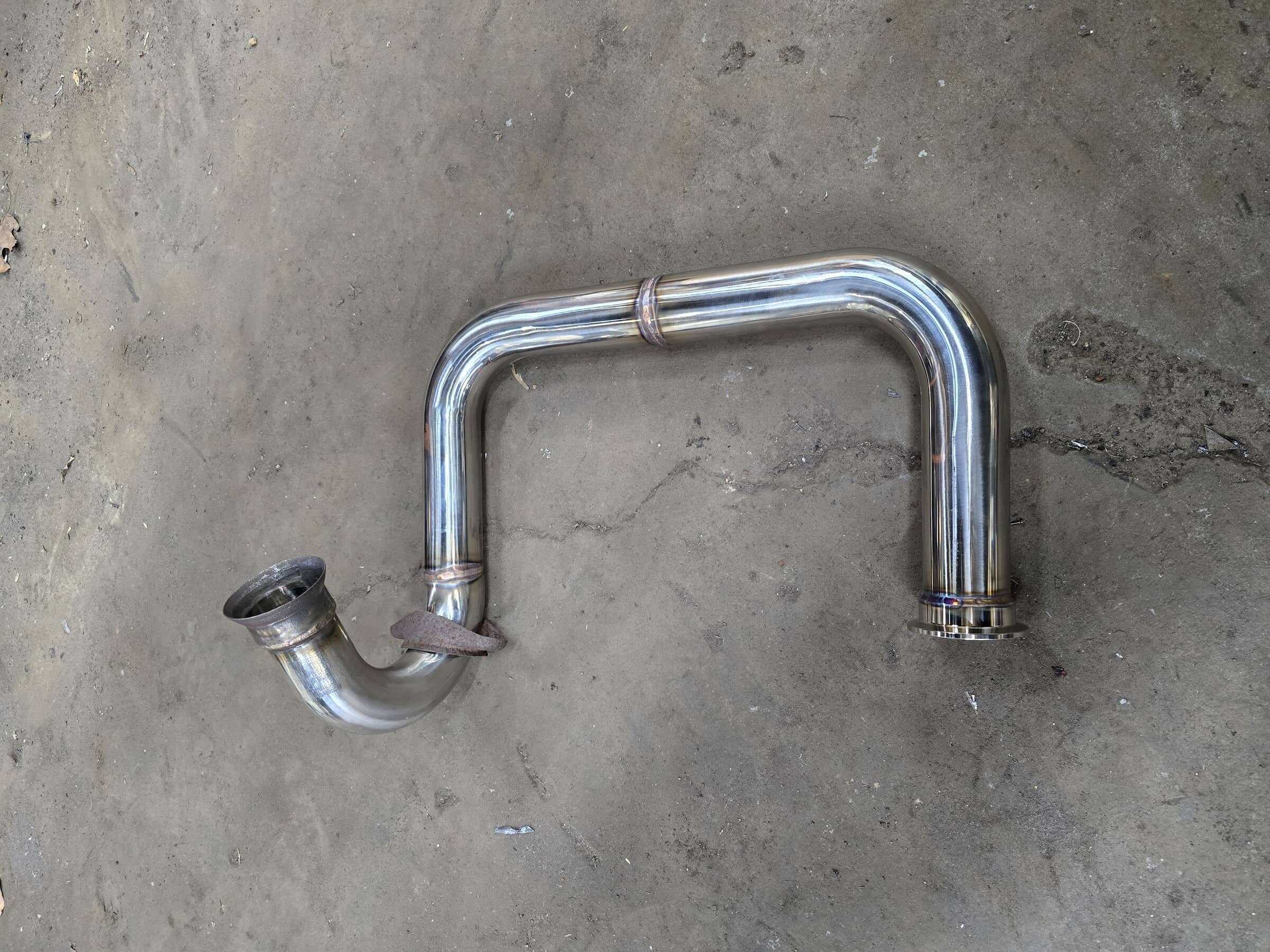 Stainless steel exhaust pipe component on a concrete floor.