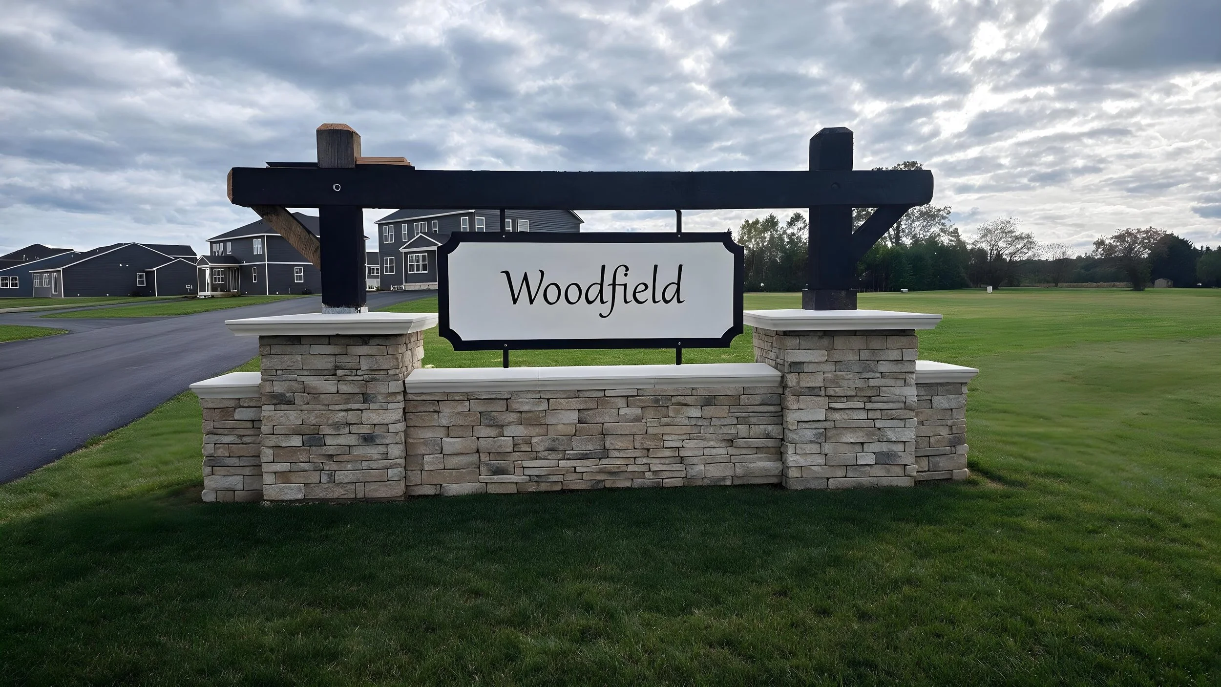 Custom monument entrance sign for Woodfield community with stone base and dimensional signage