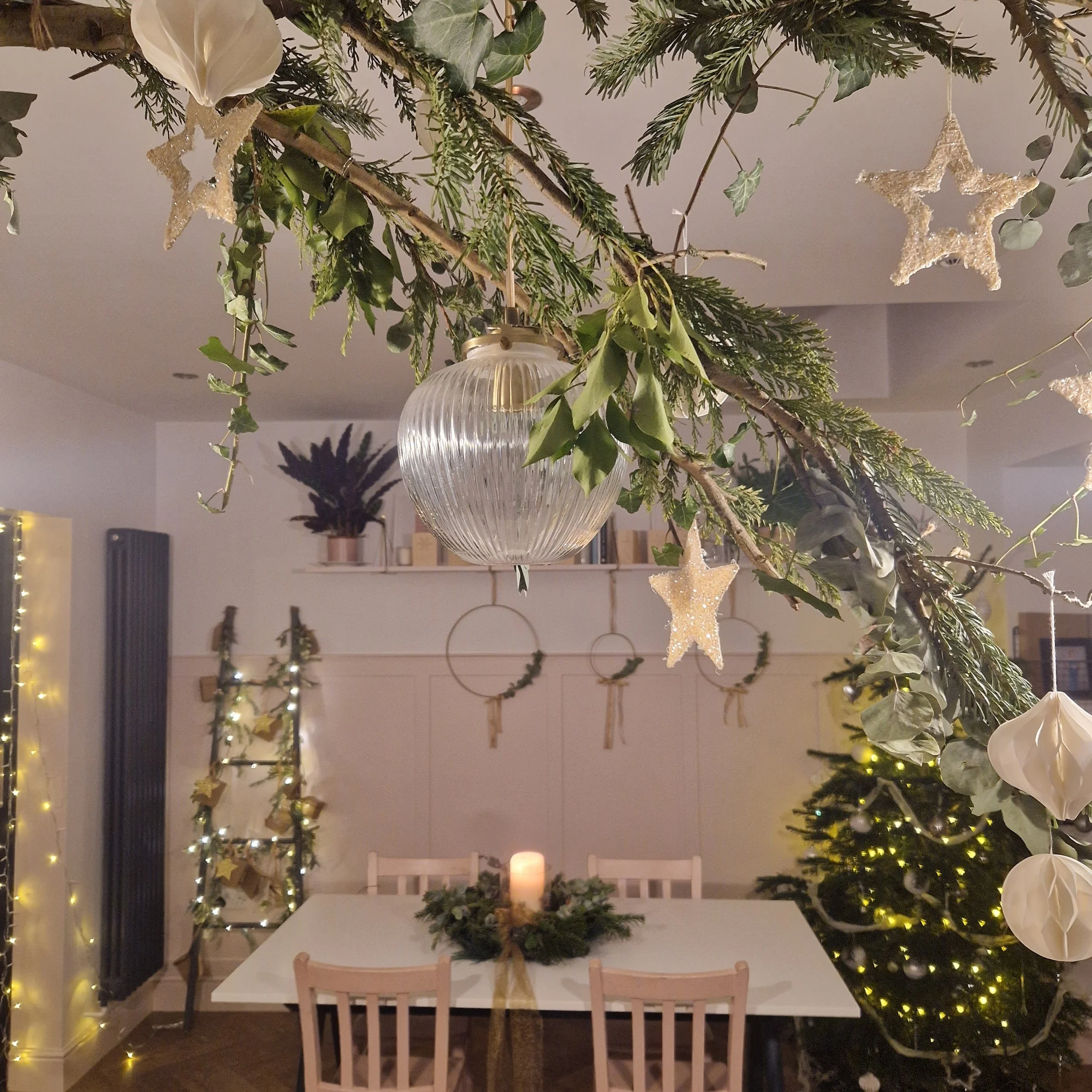A family kitchen decorated with real Christmas tree, twinkly lights and lots of greenery.