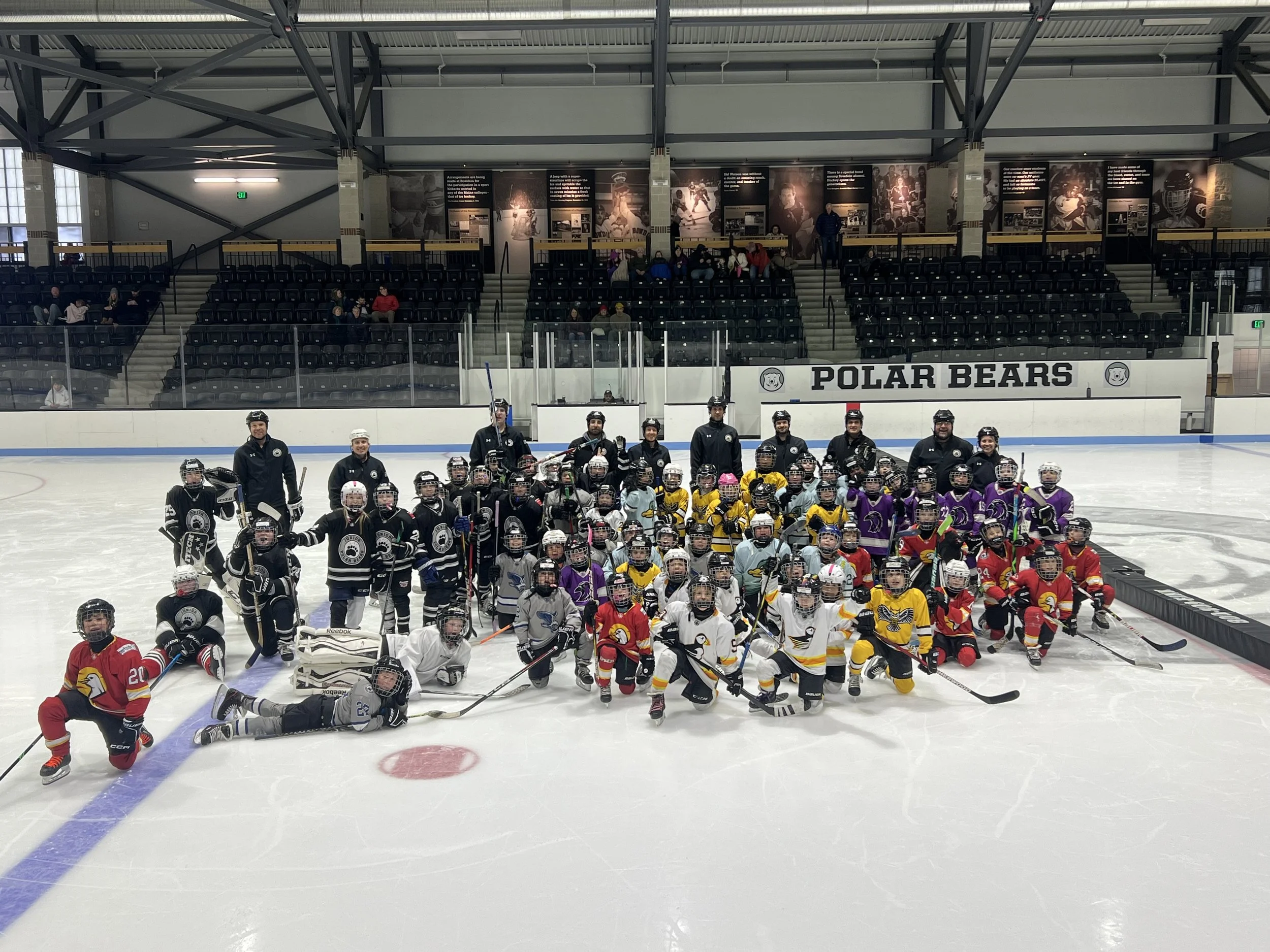 Group photo of young ice hockey players and coaches on the ice rink at Polar Bears arena.