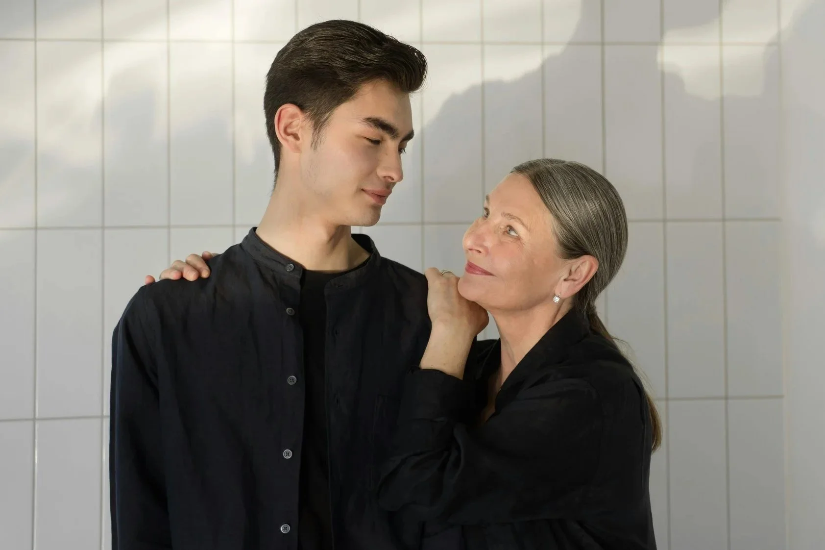 mom with gray hair smiling at young adult son