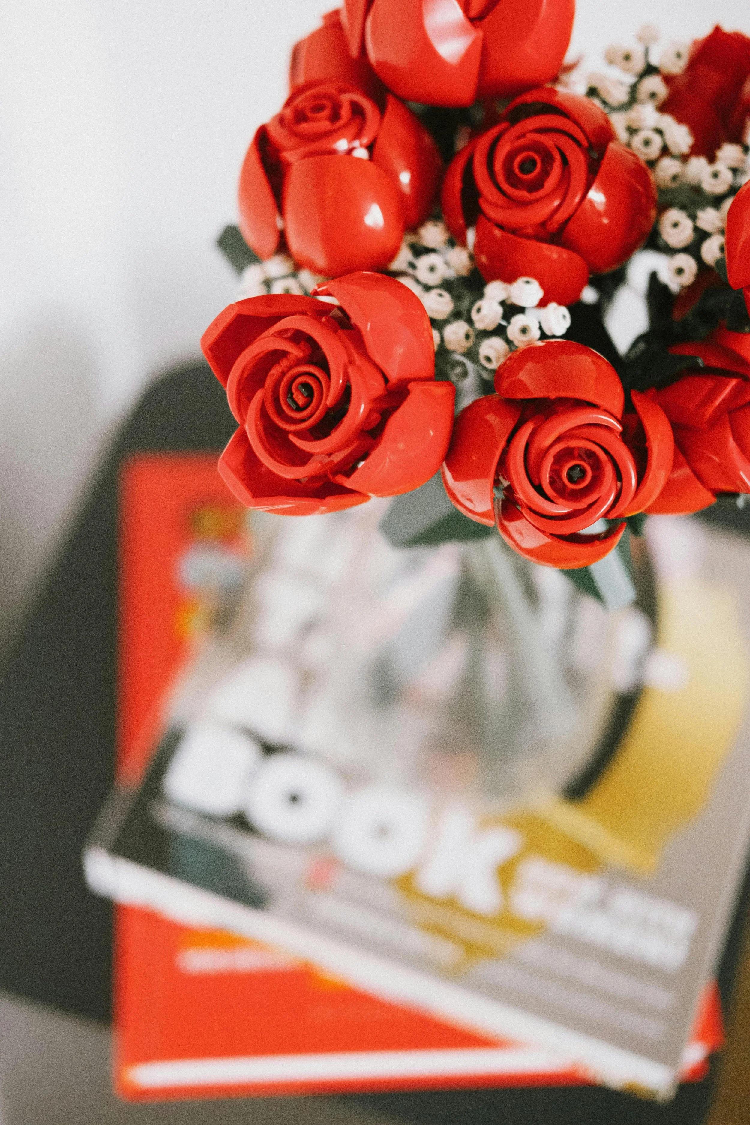 Lego red rose bouquet sitting on a pile of books