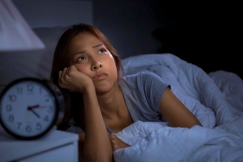 A woman who can't sleep with a clock that says 2:20am