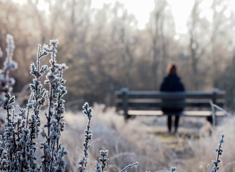 a person sitting alone on a snow bench