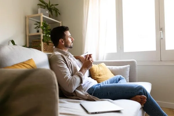 A man sitting on a sofa with a cup of coffee