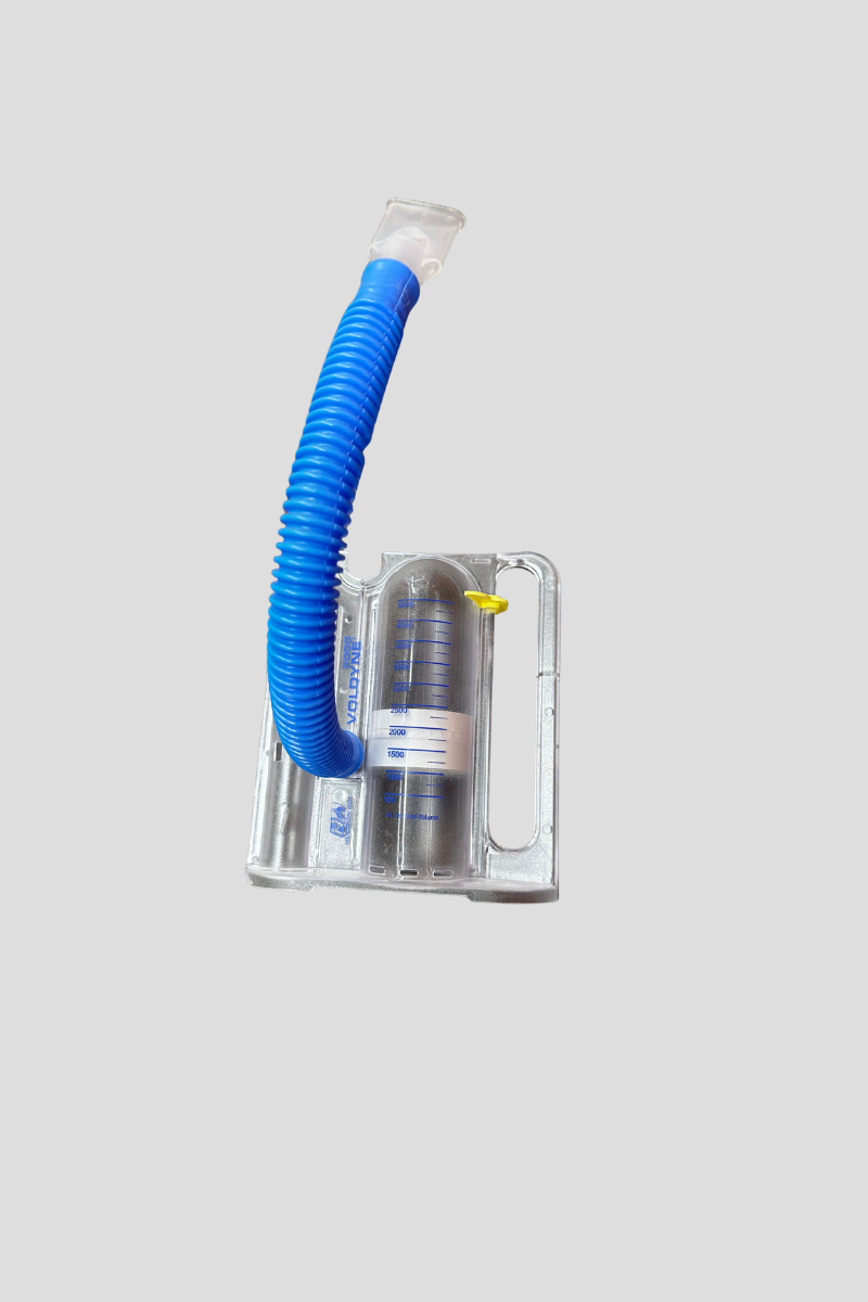 A small medical suction device with a clear container and a blue flexible tube on a speckled multicolored carpet.