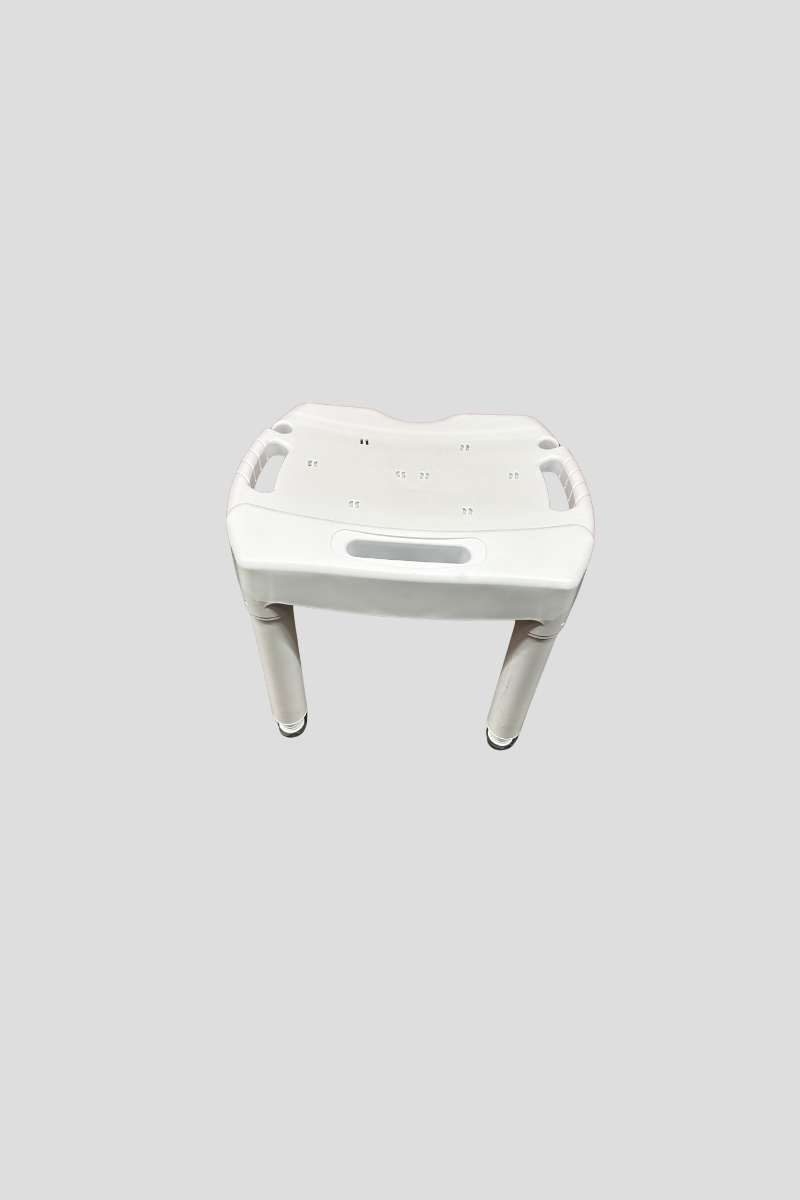 A white plastic shower seat with four legs, placed on a multi-colored carpet, in front of a red metal storage unit or door.