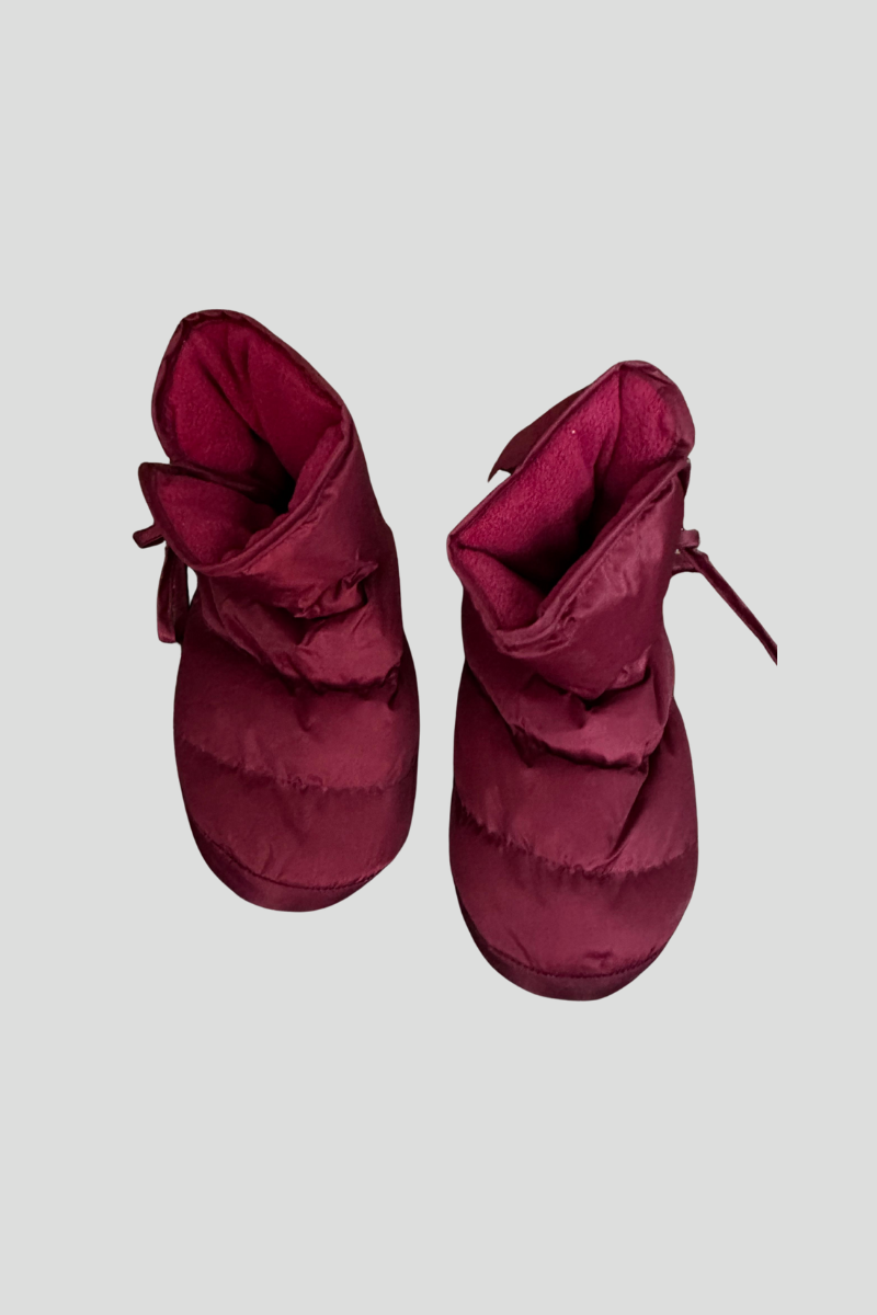 Pair of maroon winter boots with laces, placed on a multicolored speckled carpet.