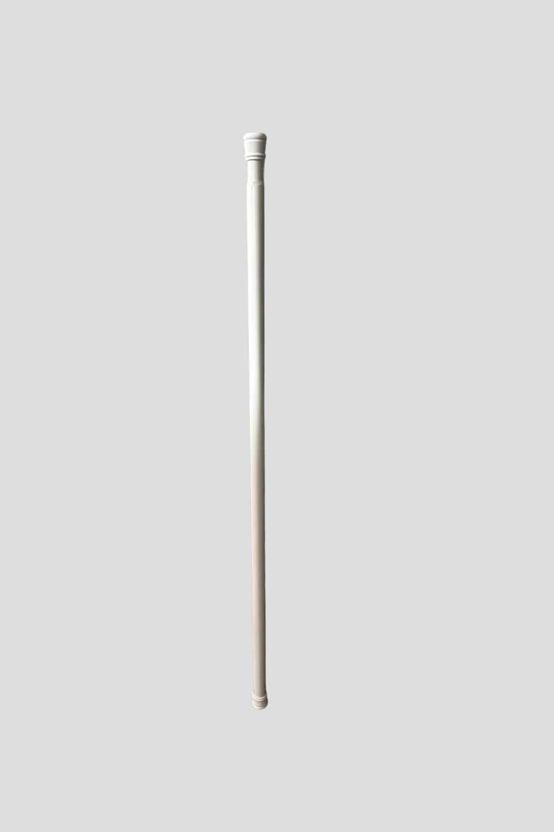 A white cane standing vertically on a brown carpeted floor against a gray metallic wall.