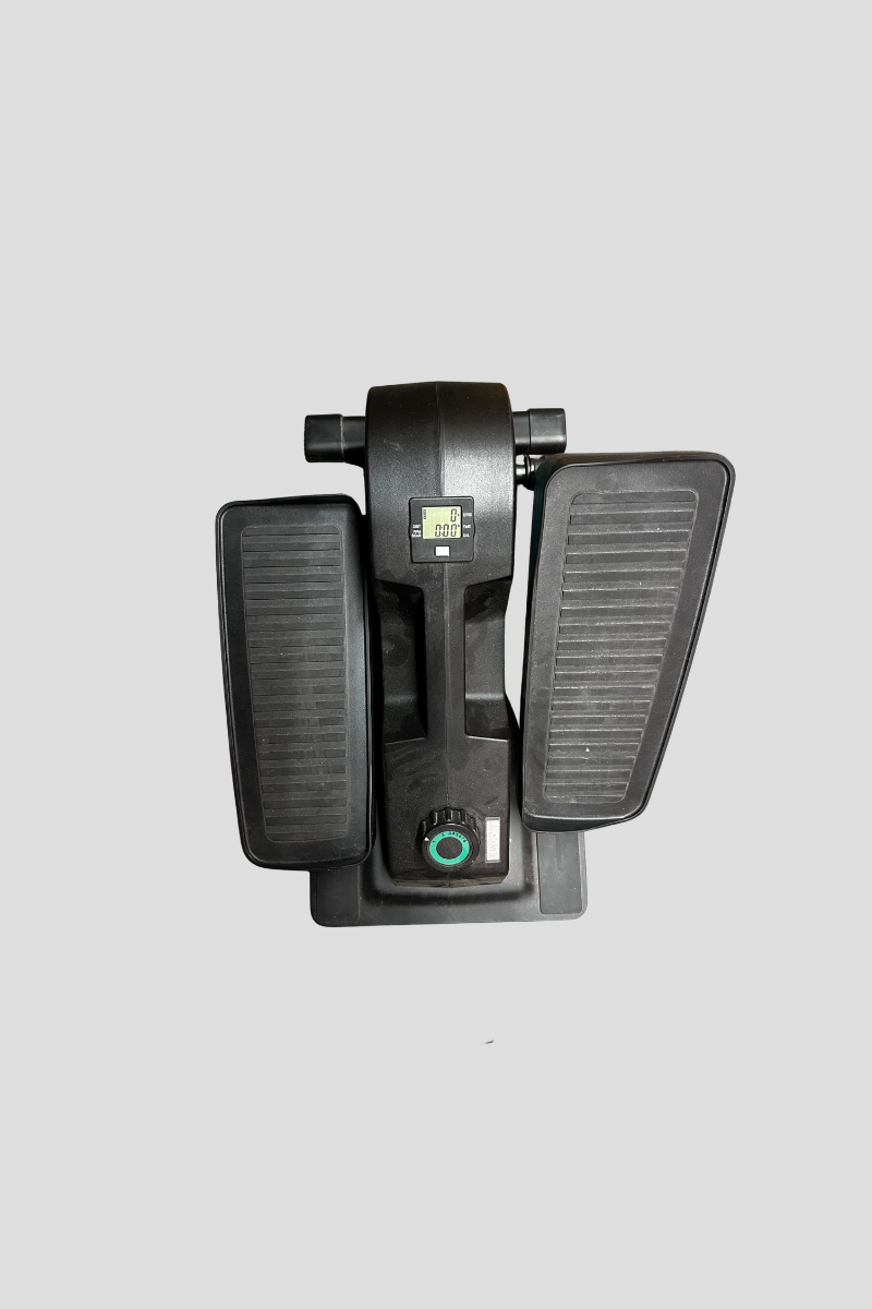 A black elliptical exercise machine with two large foot pedals, a digital display, a power cord, and a rotary knob, placed on a multicolored patterned carpet.