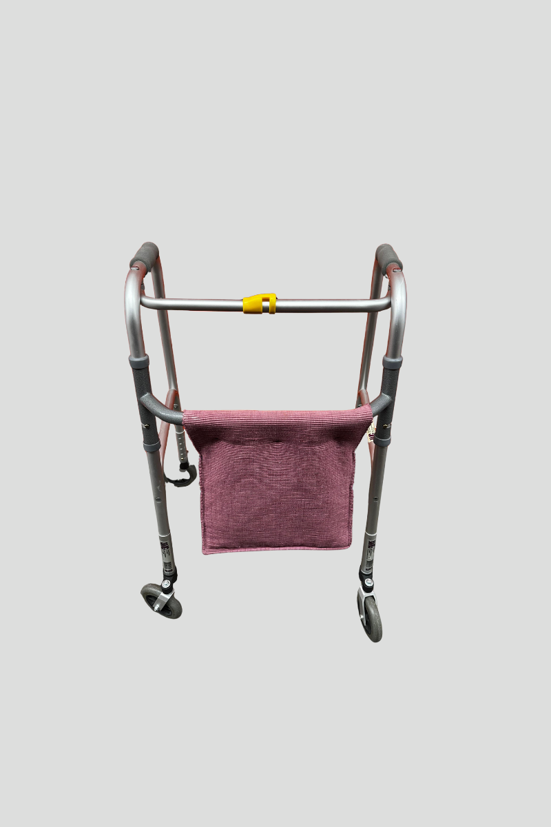 A purple walker with a fabric basket in front of a red metal shutter.