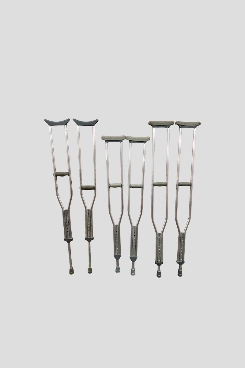 Five pairs of gray crutches leaning against a red metal roll-up door with the U-Haul logo.