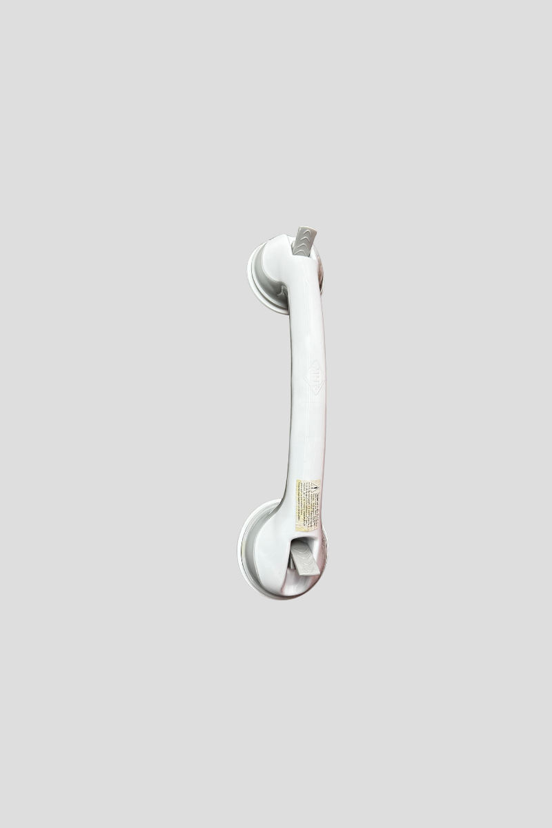 A white plastic chart book holder with two circular ends connected by a straight bar, lying on a multicolored carpet.
