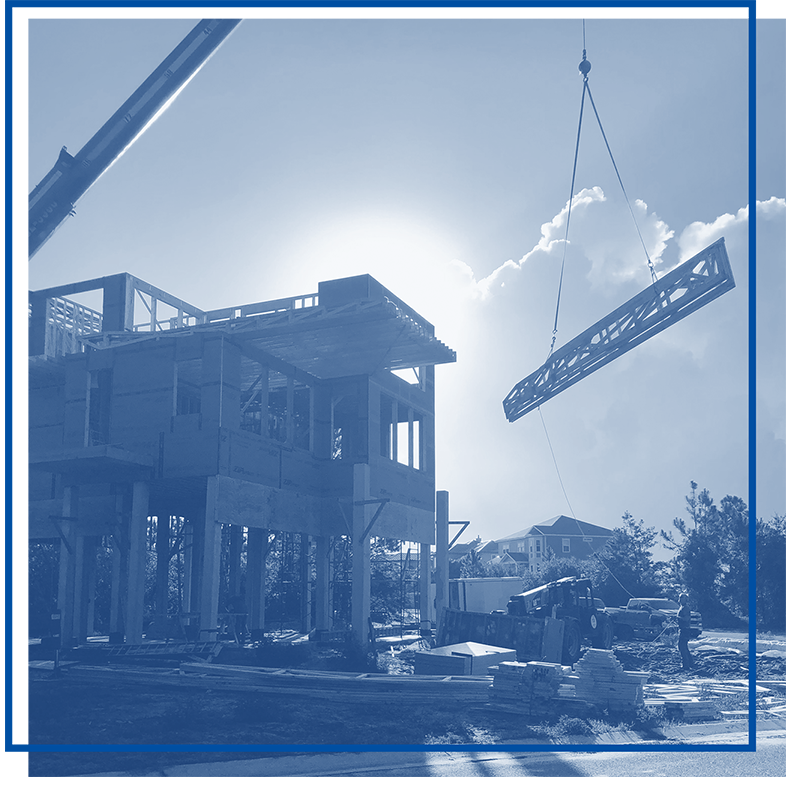 Construction site with building framework and crane lifting a structural beam.