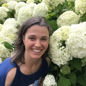 Woman smiling among white hydrangea flowers