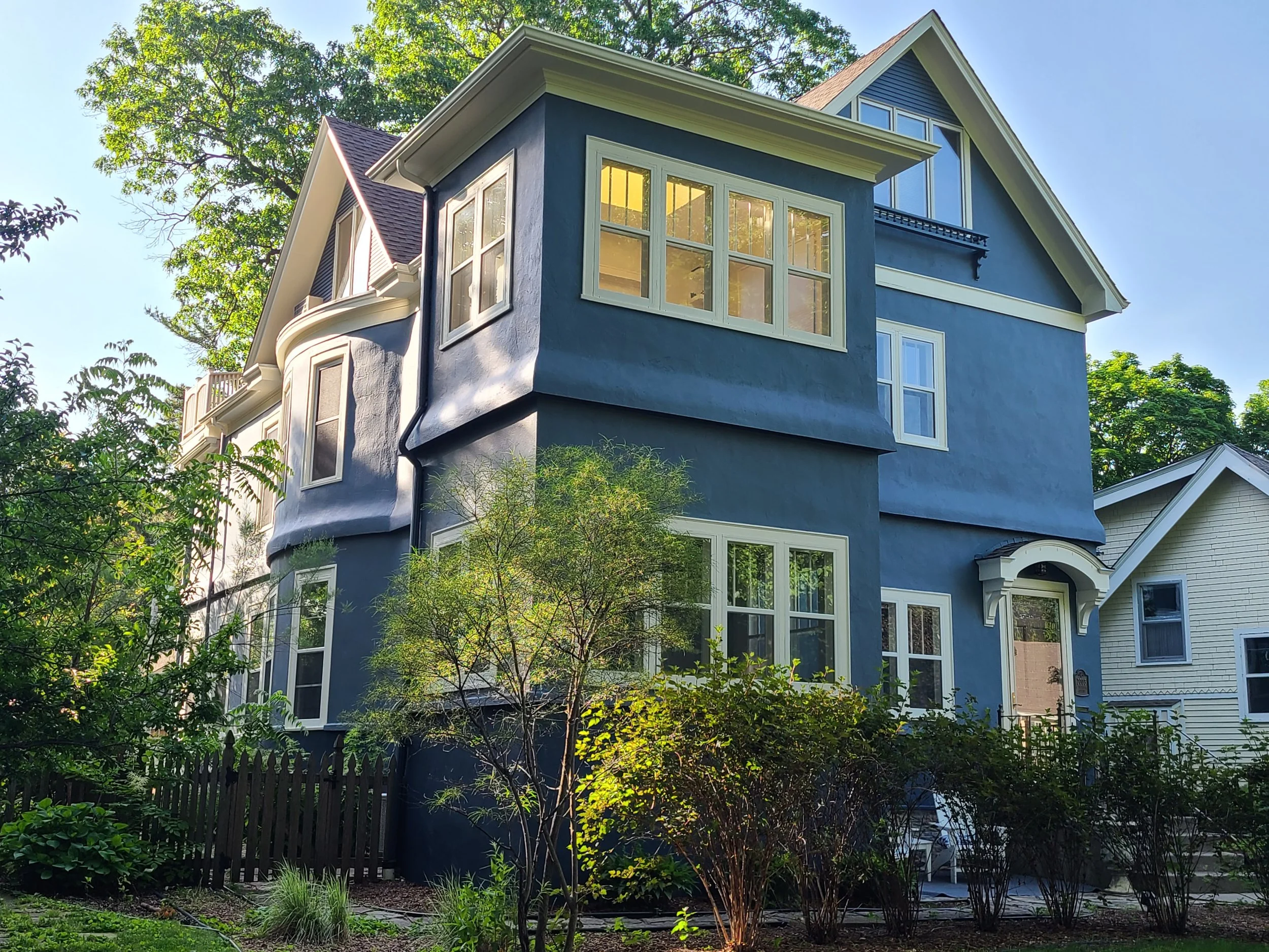 After exterior painting of a Minneapolis stucco home featuring a deep blue finish with crisp white trim.