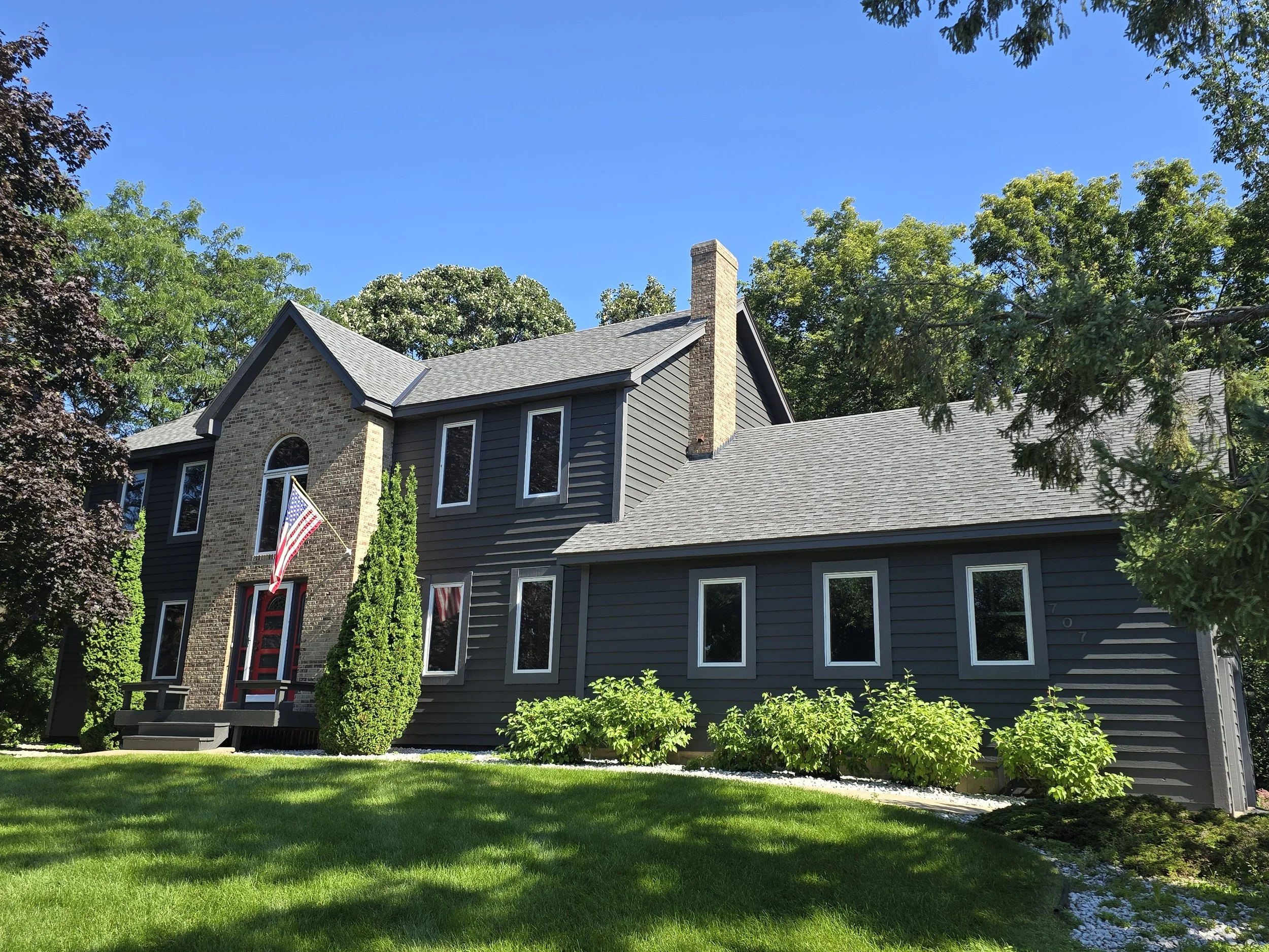 Exterior house painting project in Eagan, MN featuring dark gray siding with white trim on a two-story suburban home