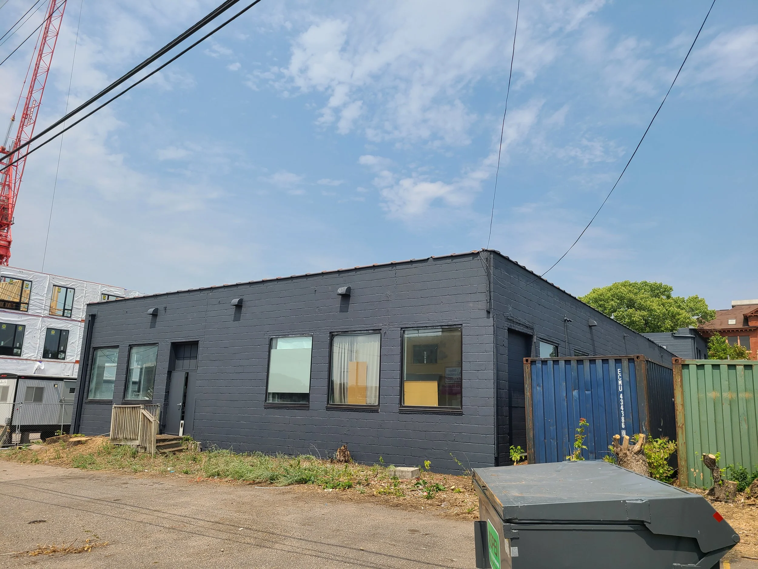 Full exterior repaint transforming a worn Northeast Minneapolis building into a bold dark charcoal commercial finish.