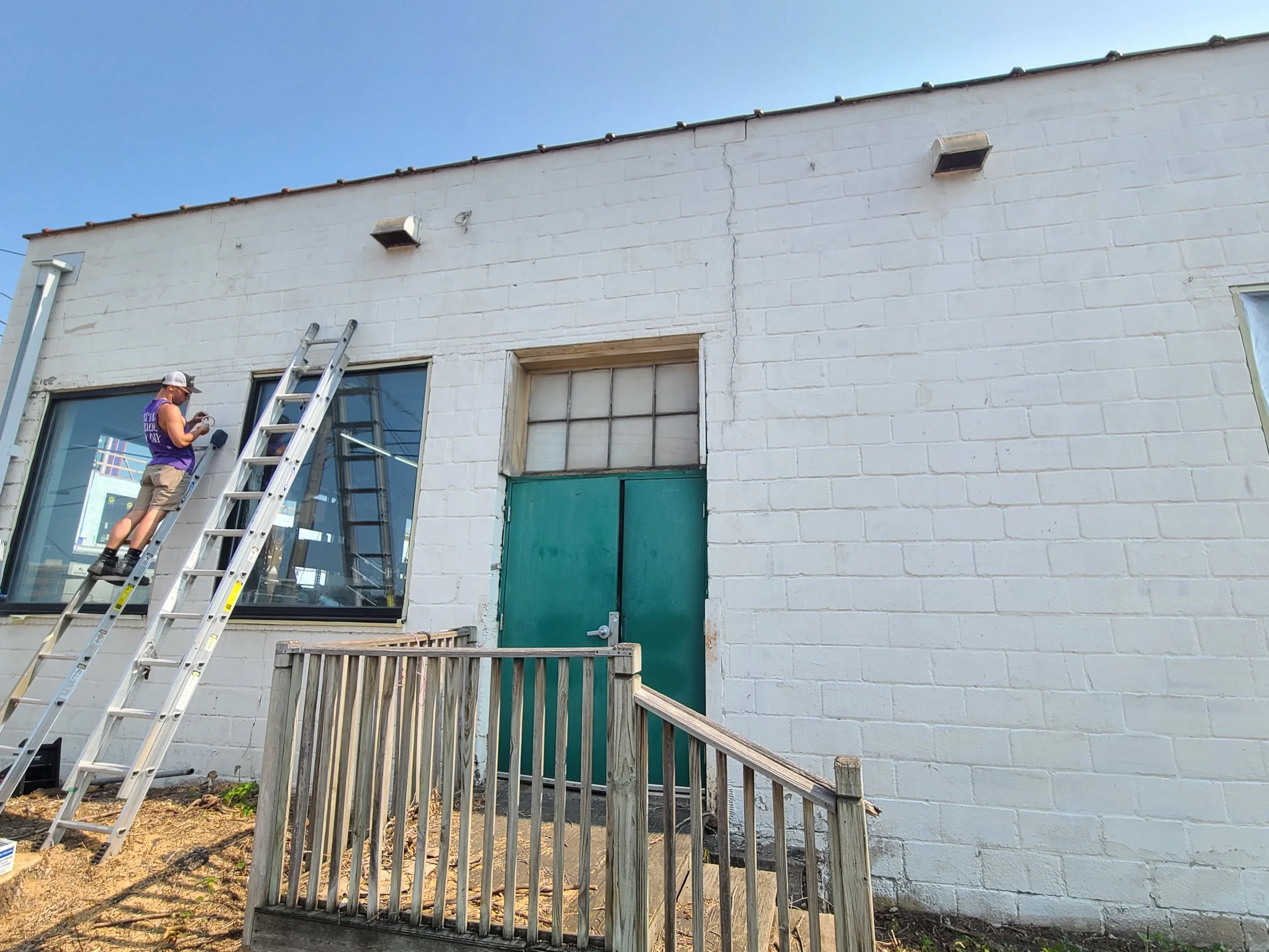 Weathered off-white exterior on a Northeast Minneapolis commercial building prior to repaint, with prep work underway.