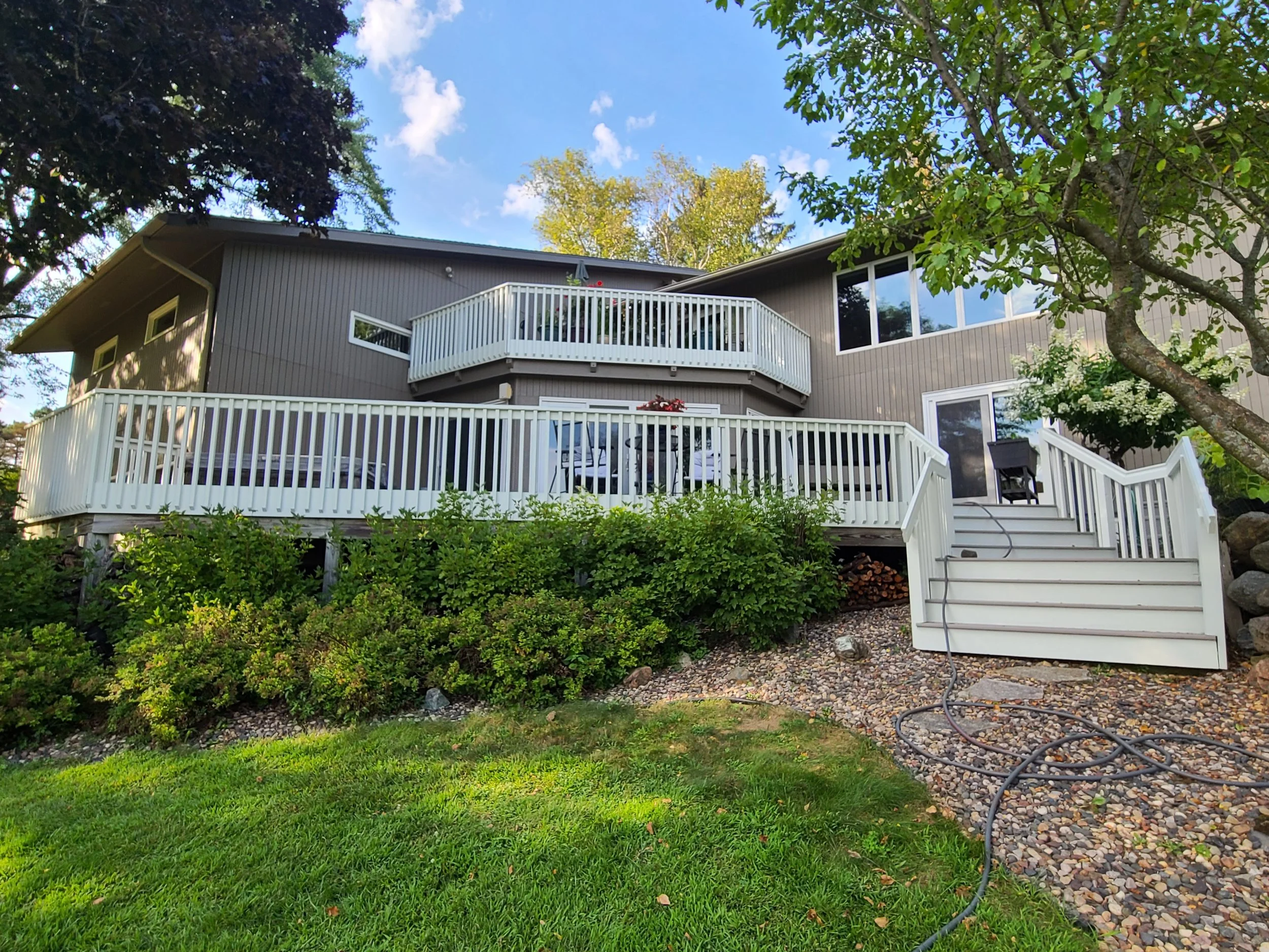 Bloomington backyard exterior painting with warm gray siding and crisp white deck rails