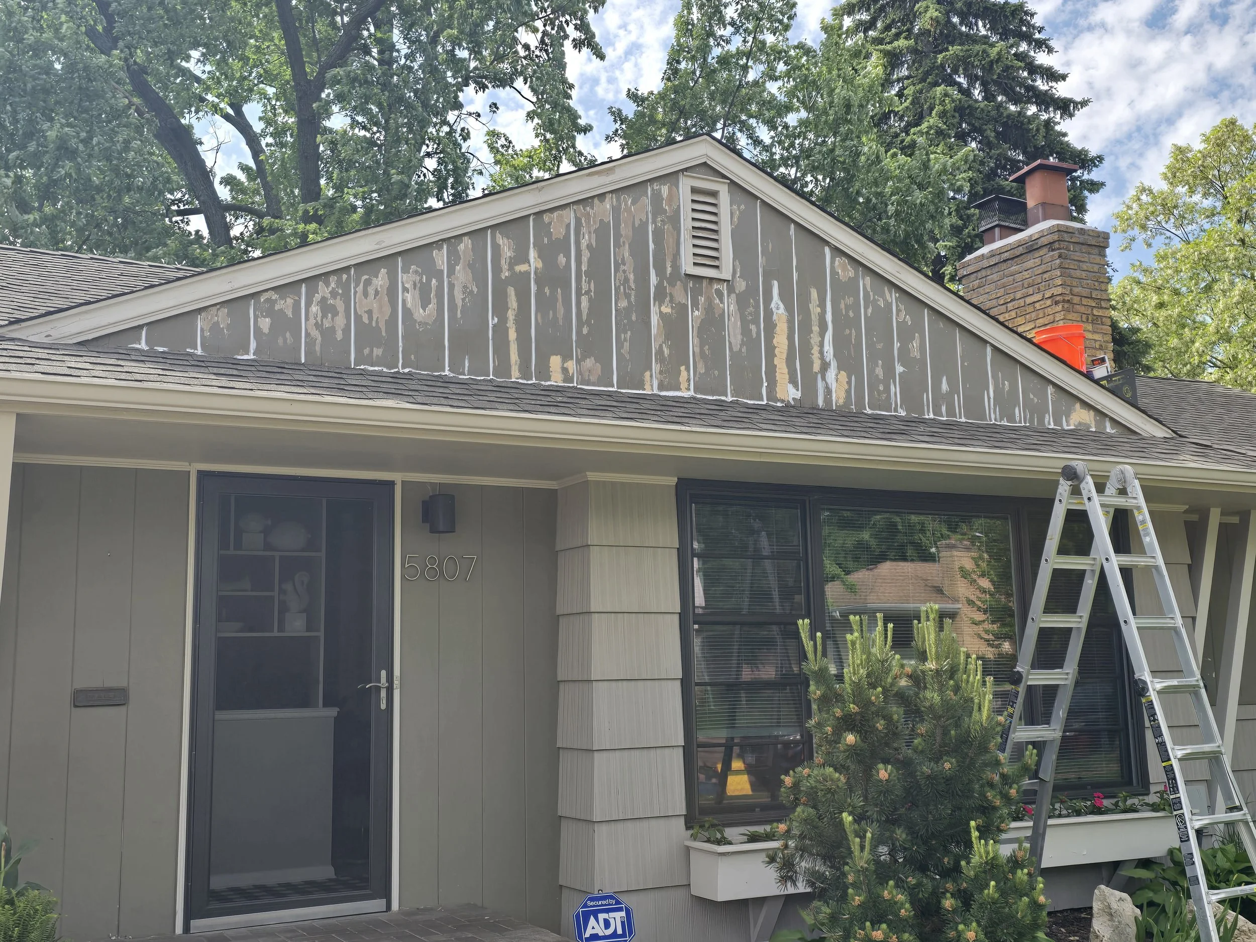 Layer by layer — washed, scraped, caulked, wood filler, Bondo, sanded. Primer and two coats followed on this Kenny neighborhood gable.