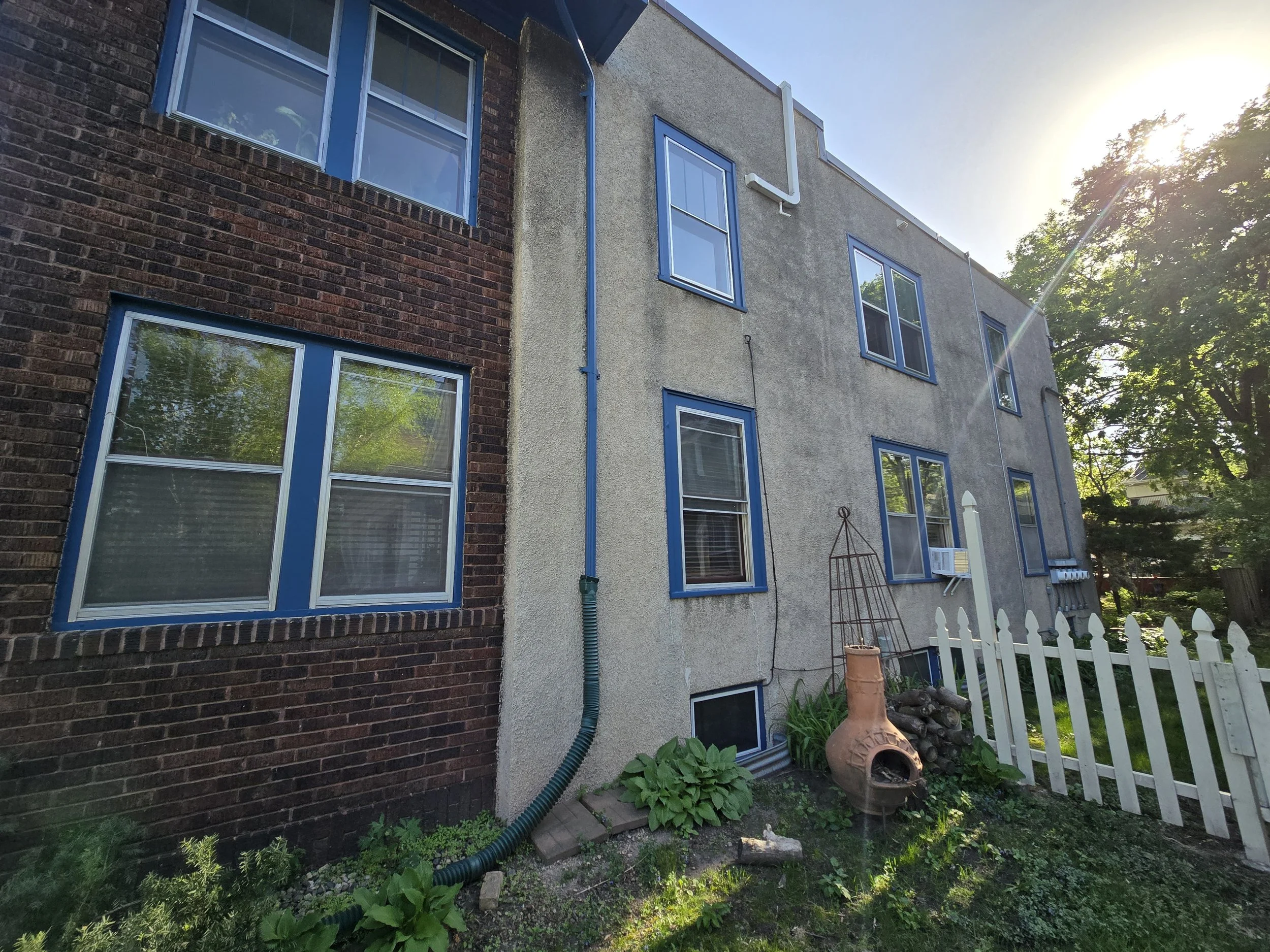 Uptown Minneapolis fourplex prior to exterior refresh, with aging stucco, trim, and weathered brick surfaces.