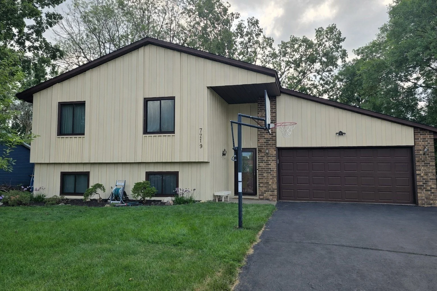 Beige exterior repaint on a Bloomington split-level with vertical siding and dark trim contrast