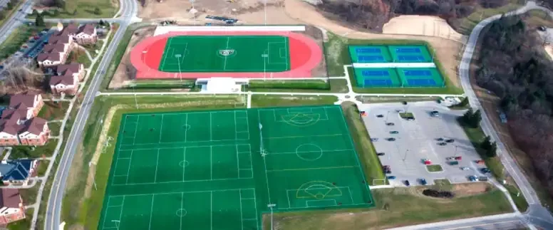 Aerial view of sports facilities including soccer fields, tennis courts, and a running track in a residential area.