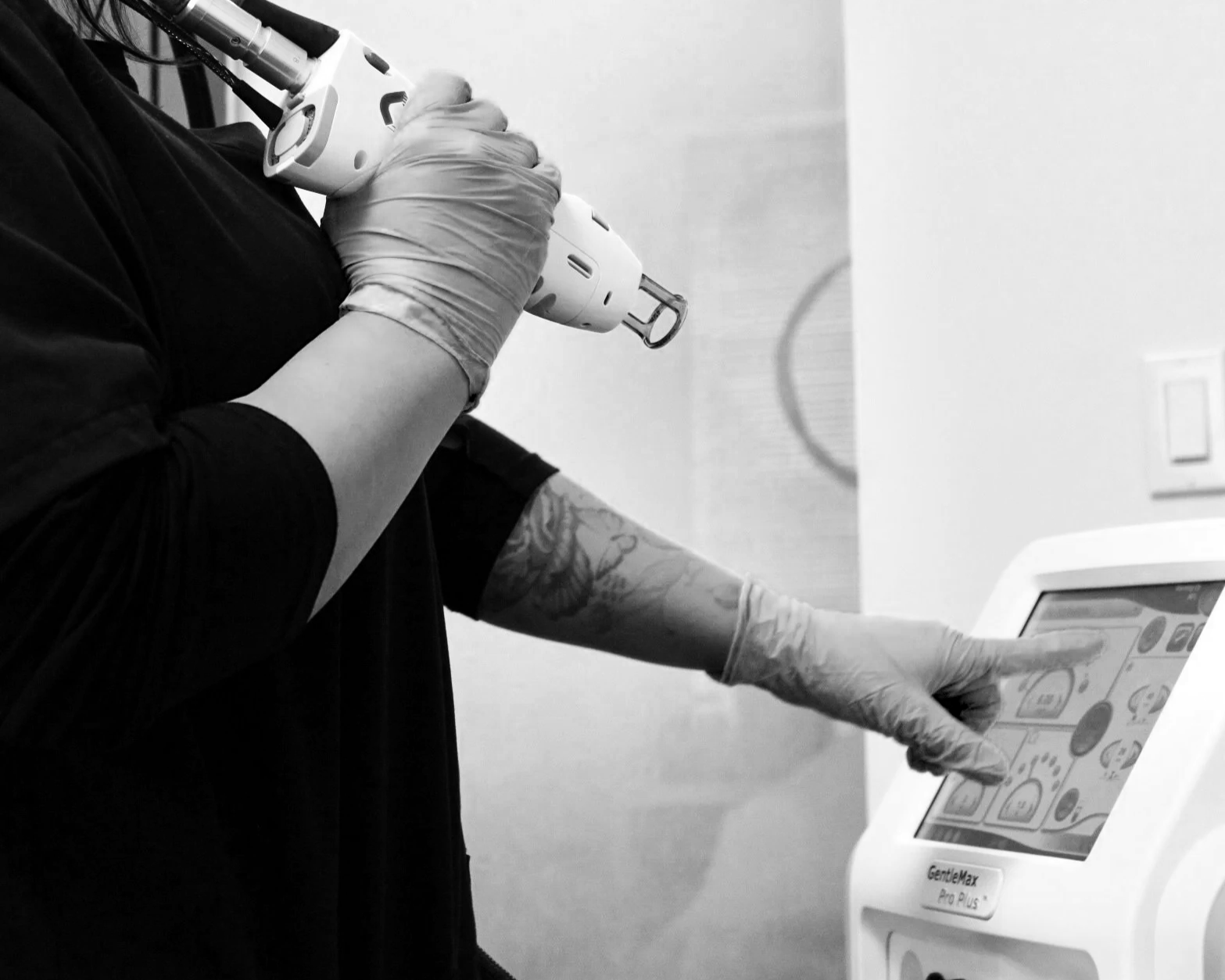 A person holding a medical device in a medical setting, with various medical equipment and supplies nearby.
