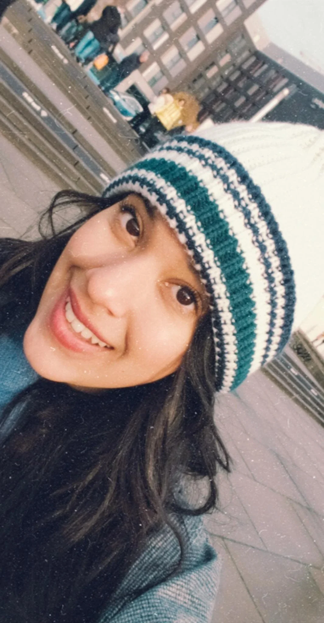 Person smiling in a striped knit hat outdoors.