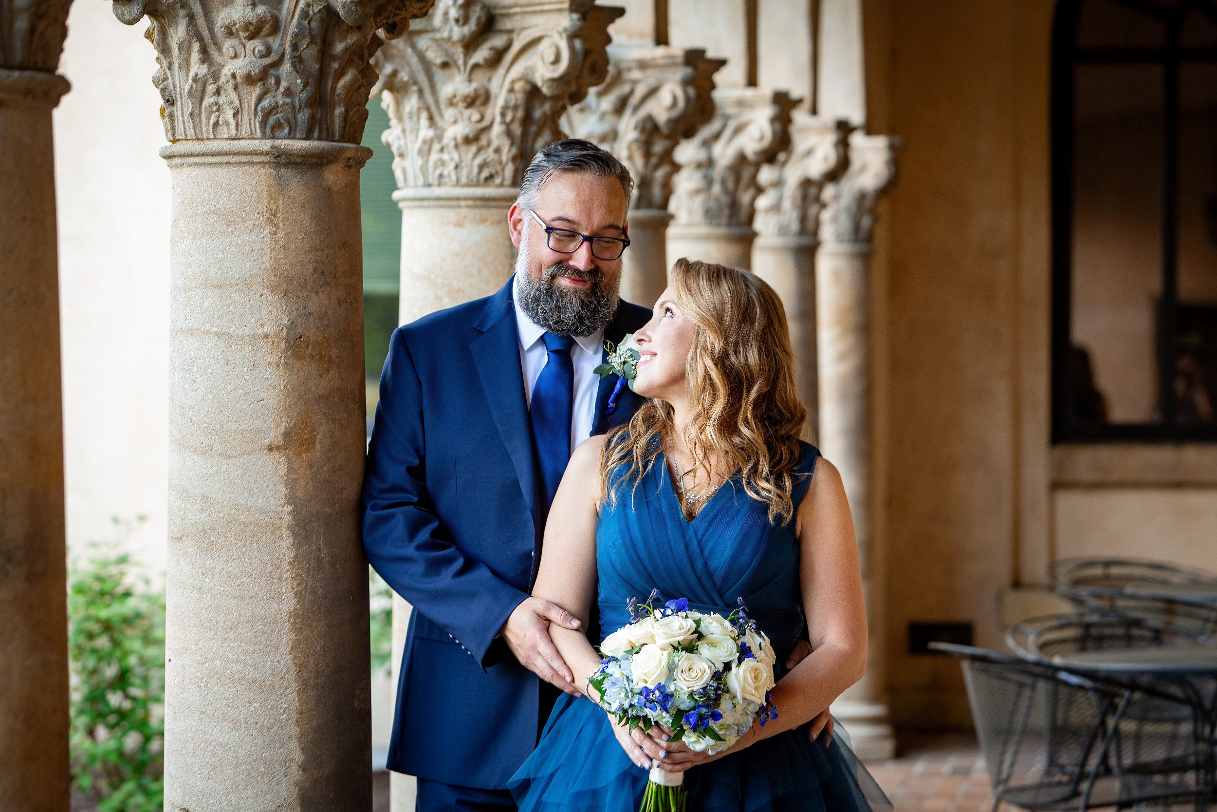 A couple dressed in formal attire stand by ornate stone columns. Wedding Venue: Unity Village -- Experience old European elegance and natural beauty -- Located in Lees Summit, MO.