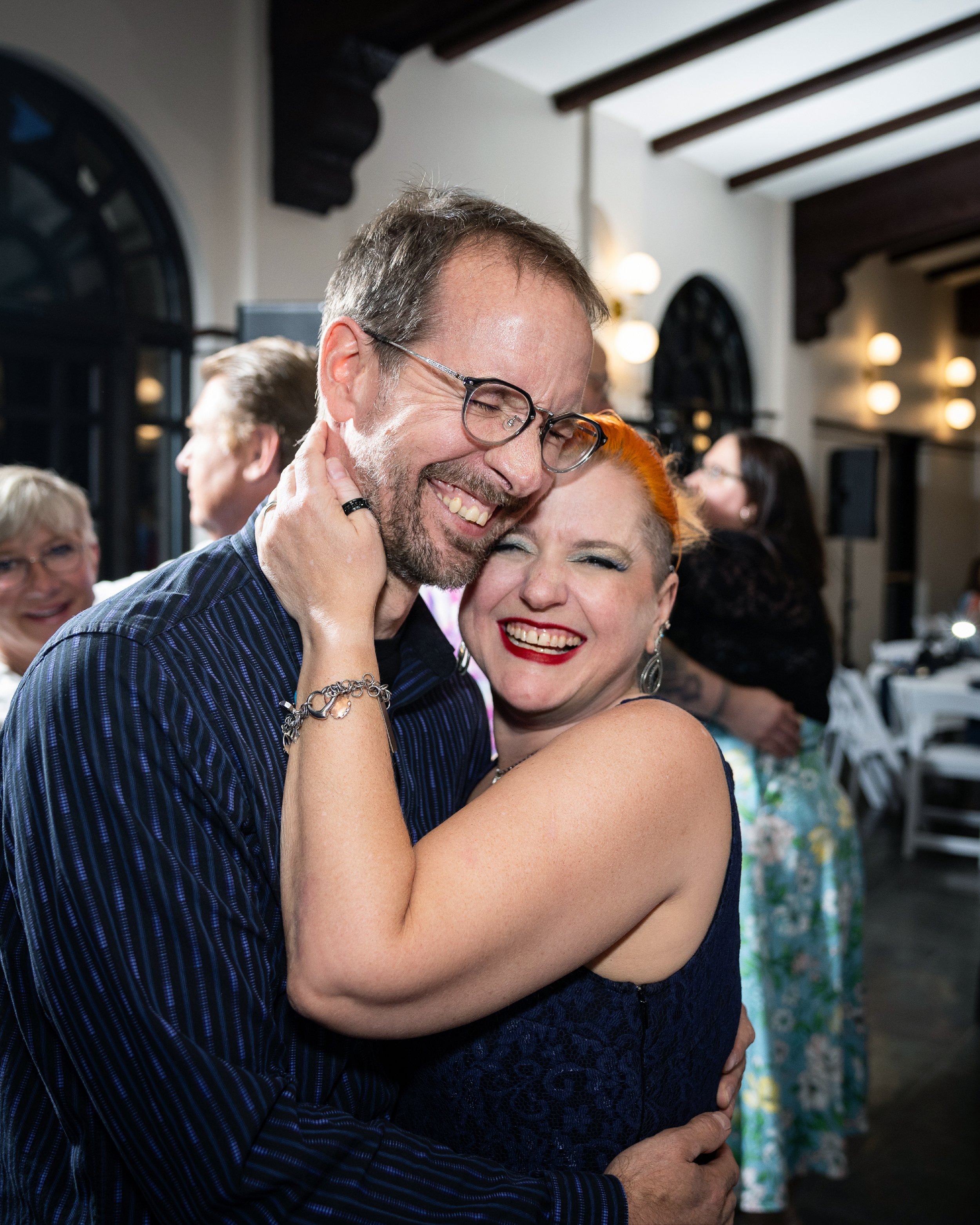 A smiling couple embraces at a party or event. Wedding Venue: Unity Village -- Experience old European elegance and natural beauty -- Located in Lees Summit, MO.
