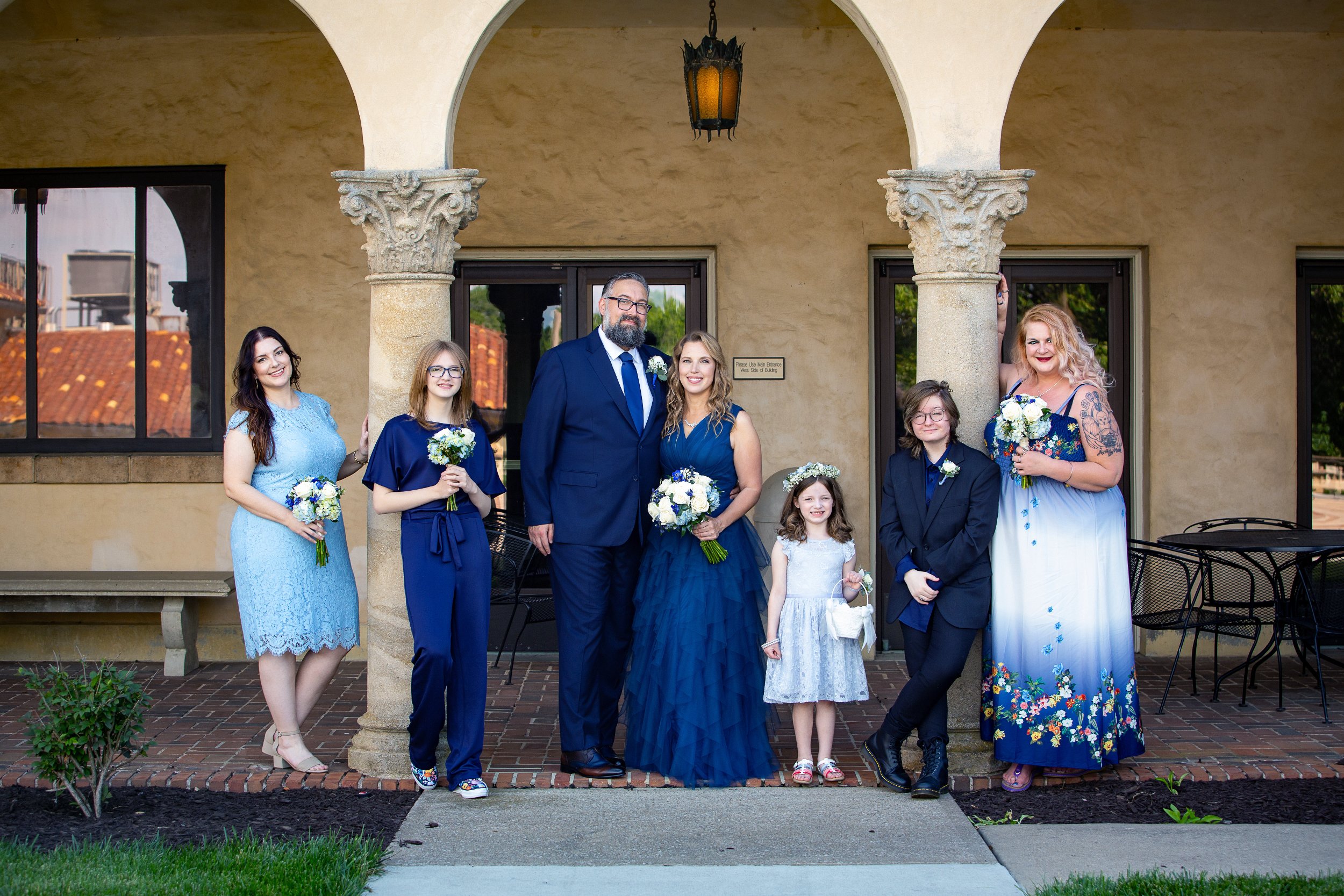 A group of seven people, dressed in formal attire, pose for a wedding photo. Wedding Venue: Unity Village -- Experience old European elegance and natural beauty -- Located in Lees Summit, MO.