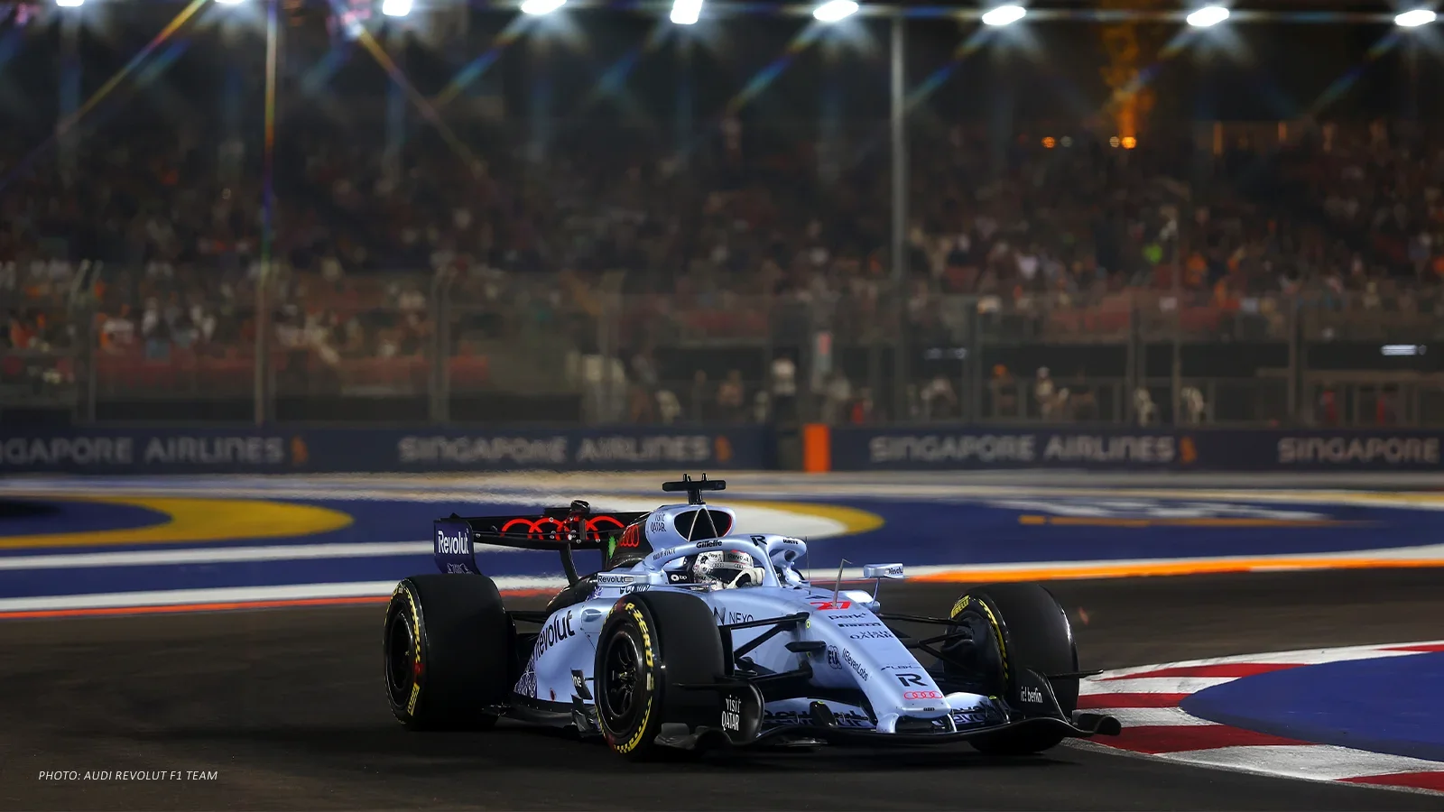 Nico Hülkenberg drives the silver No. 27 Audi through a corner under the lights in Singapore.
