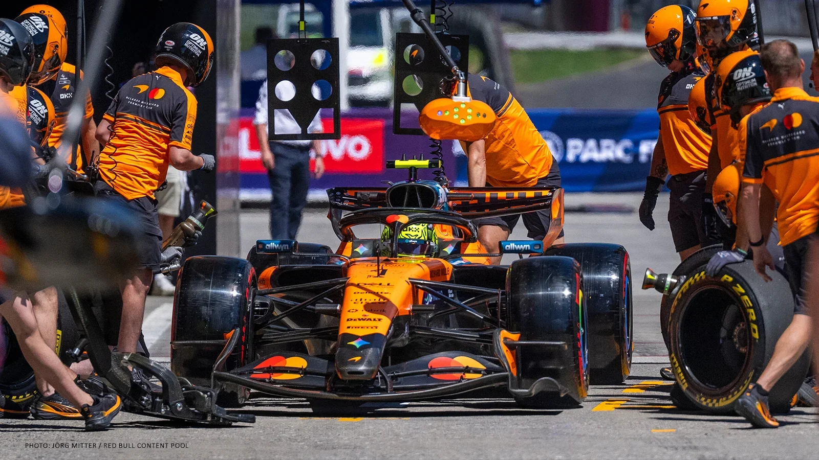 Lando Norris in his McLaren while team members work around the car in the pit lane.