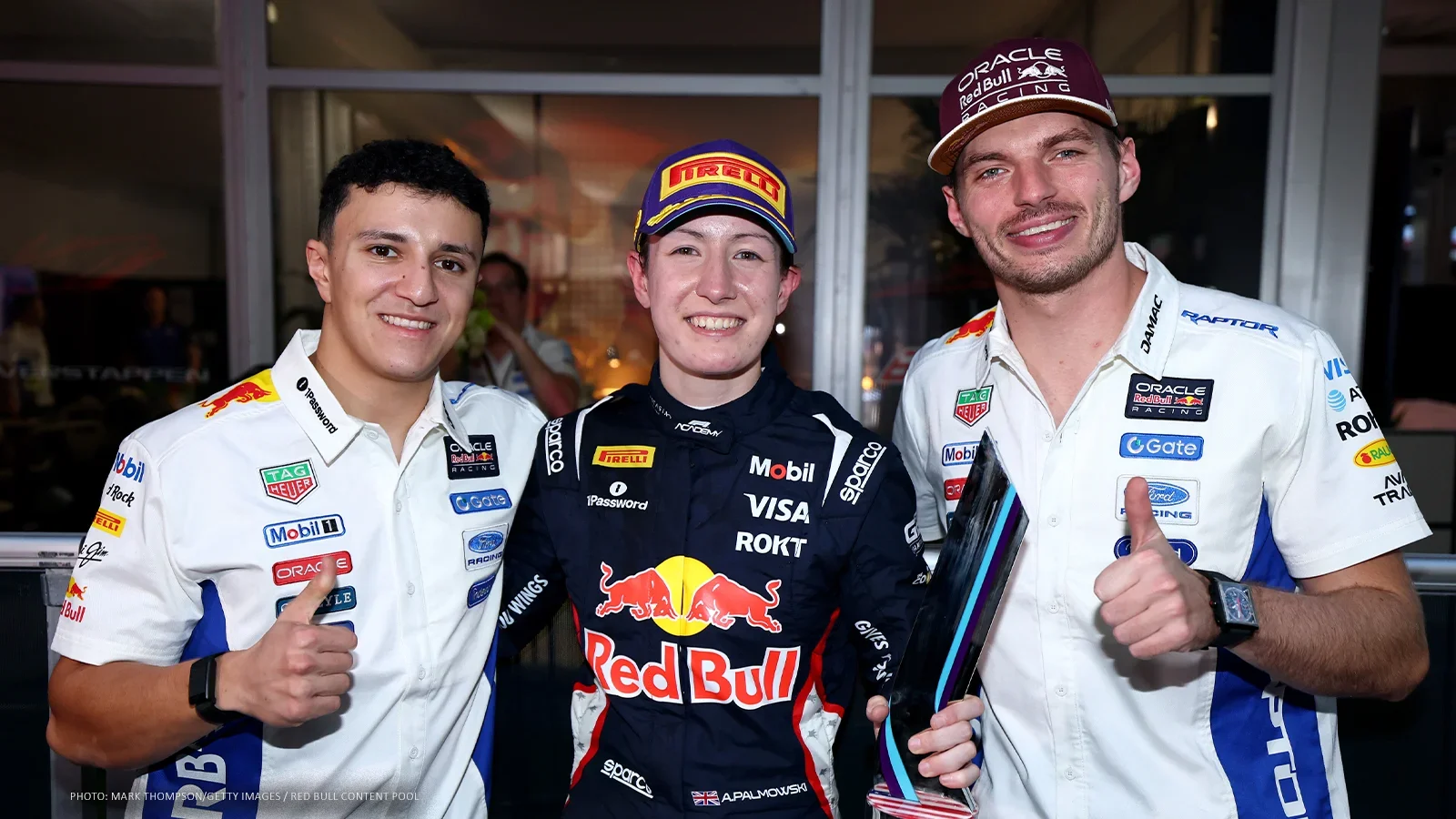 Alisha Palmowski holding her second-place race trophy between Isack Hadjar and Max Verstappen after clinching the 2026 F1 Academy title in Austin.
