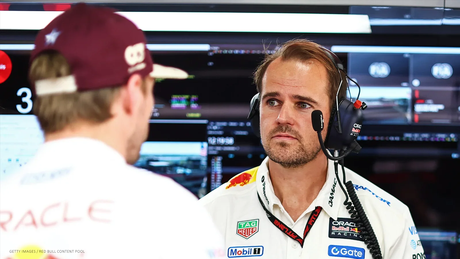 Tom Hart, wearing a headset, speaks with Max Verstappen in the Red Bull garage.