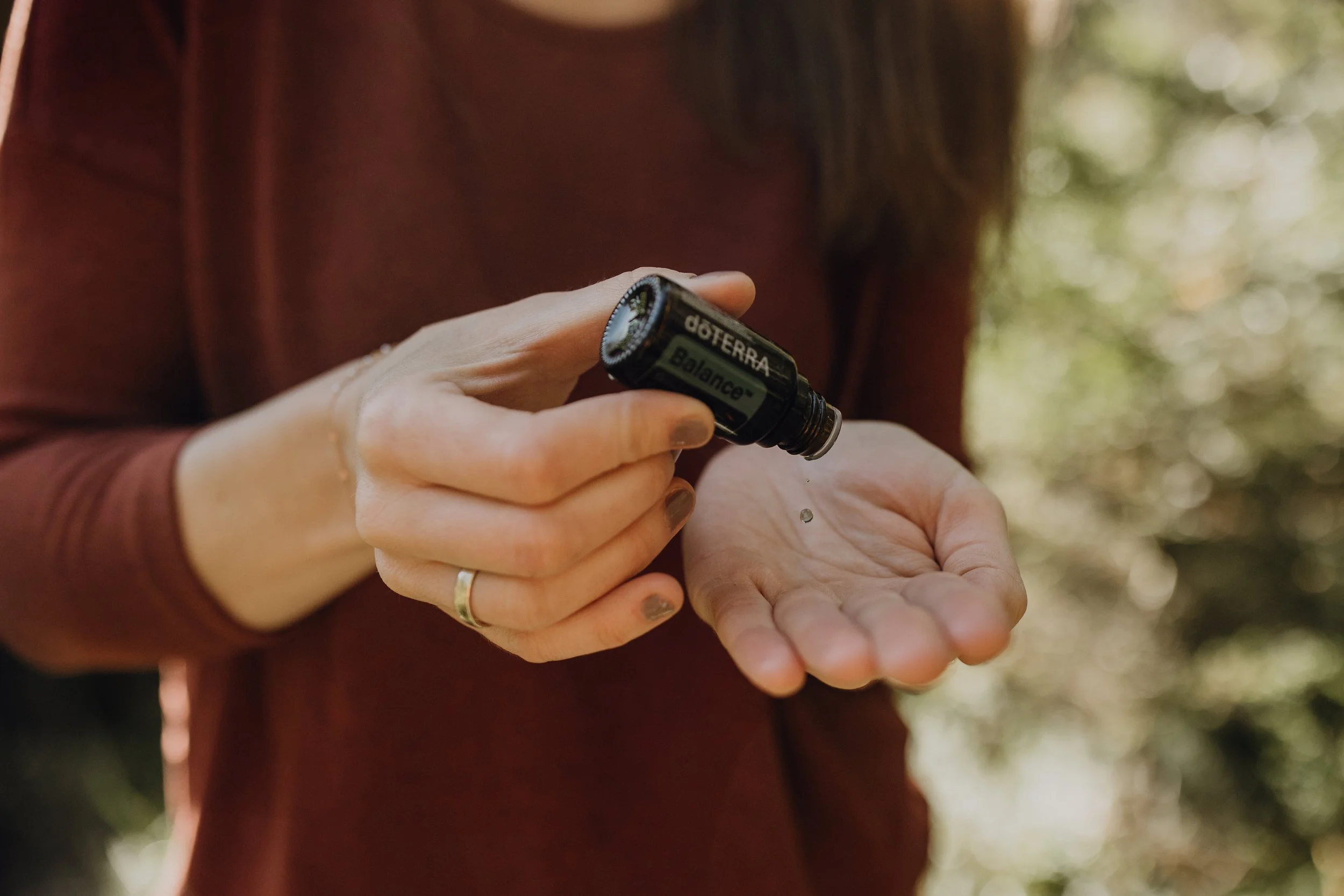 Eine Frau gibt sich einen Tropfen Balance Öl von doterra auf die Hand