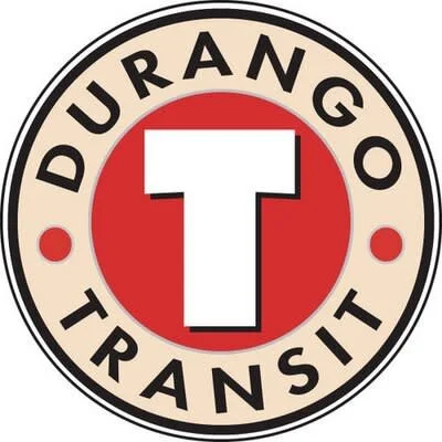 A red DuraGo Transit vehicle, possibly a trolley or tram, parked on a sidewalk with windows and advertising text.