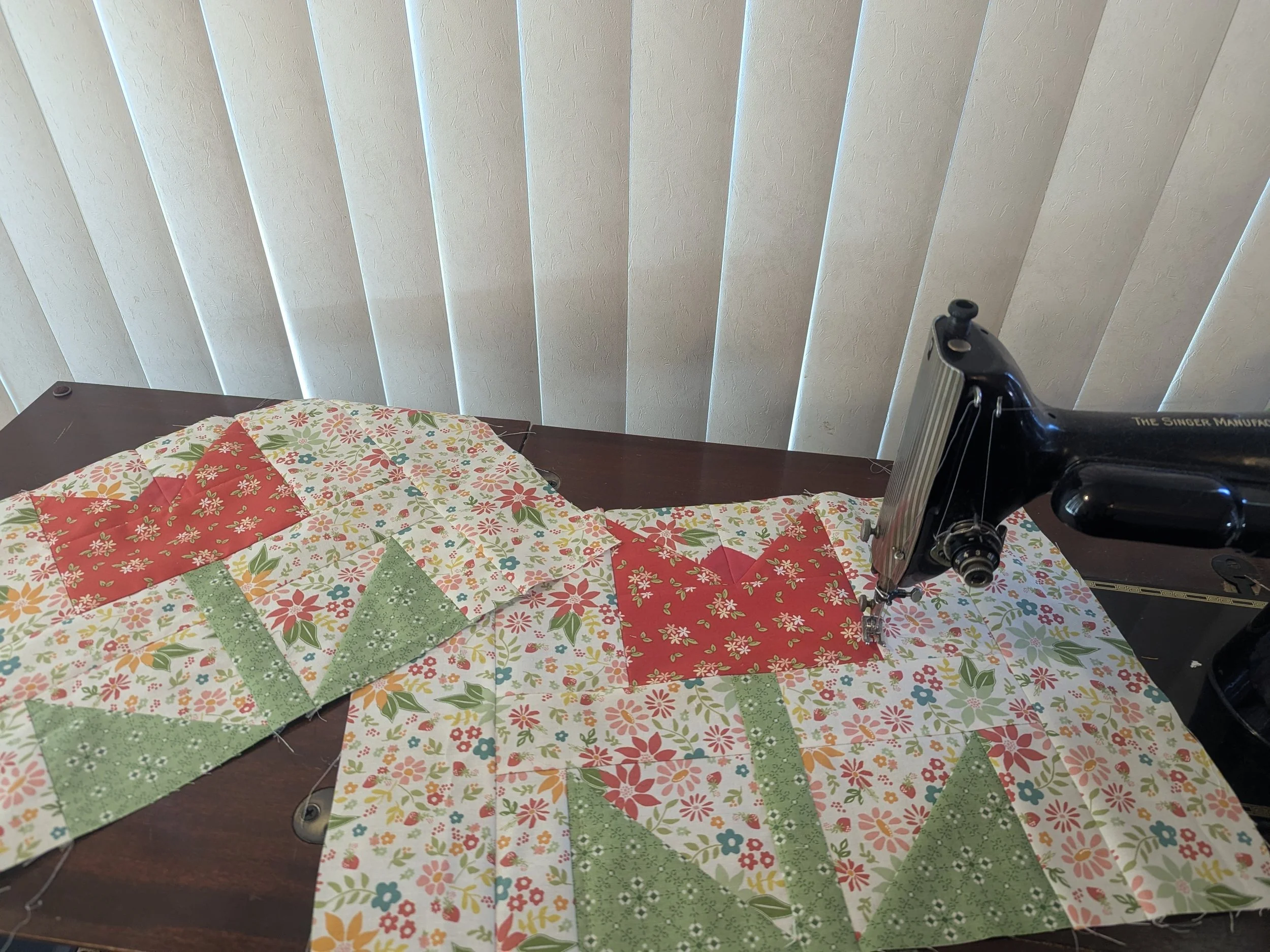 2 tulip quilt blocks sitting with vintage singer sewing machine