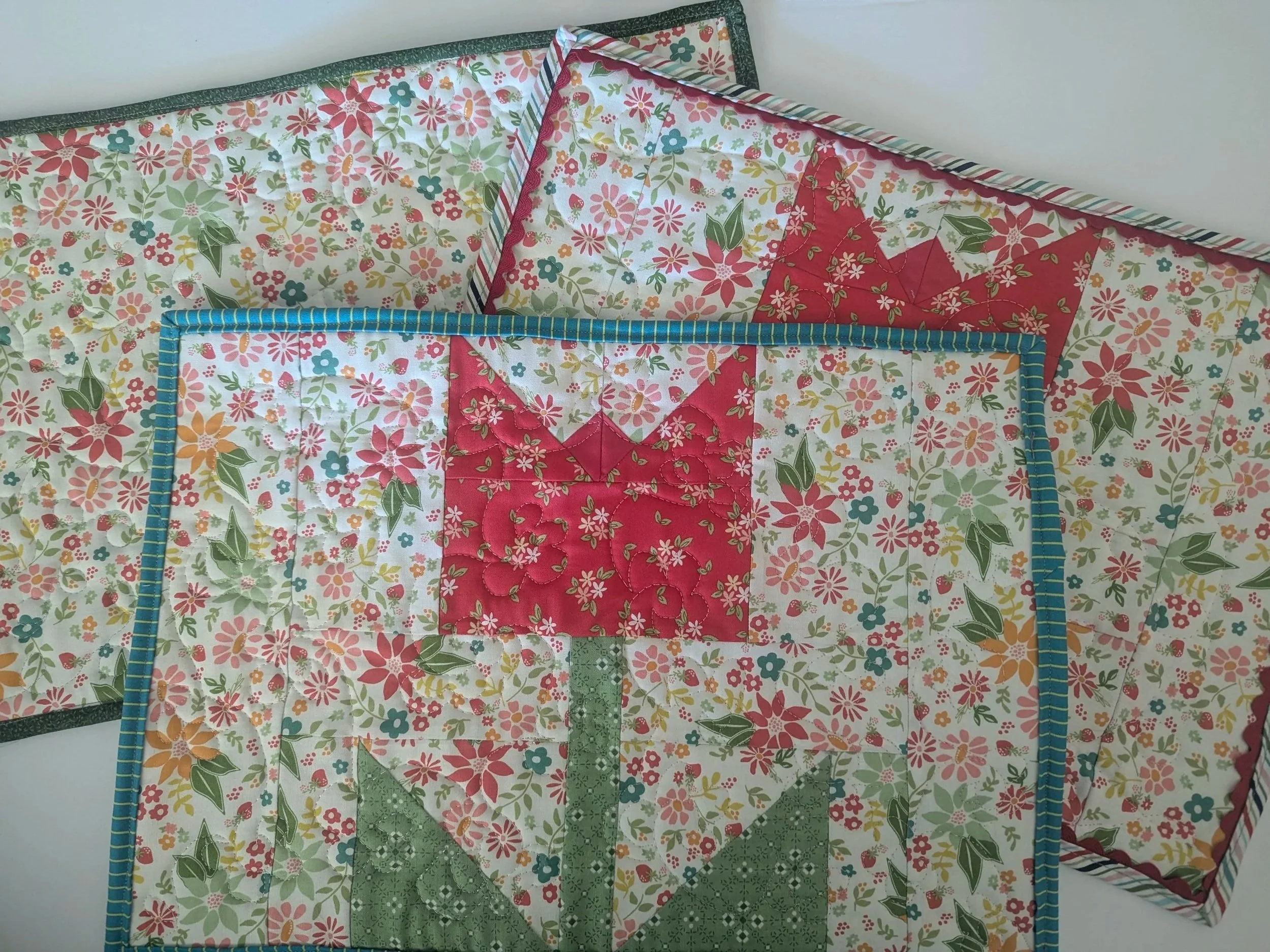3 quilted placemants overlapping with red tulip in the middle