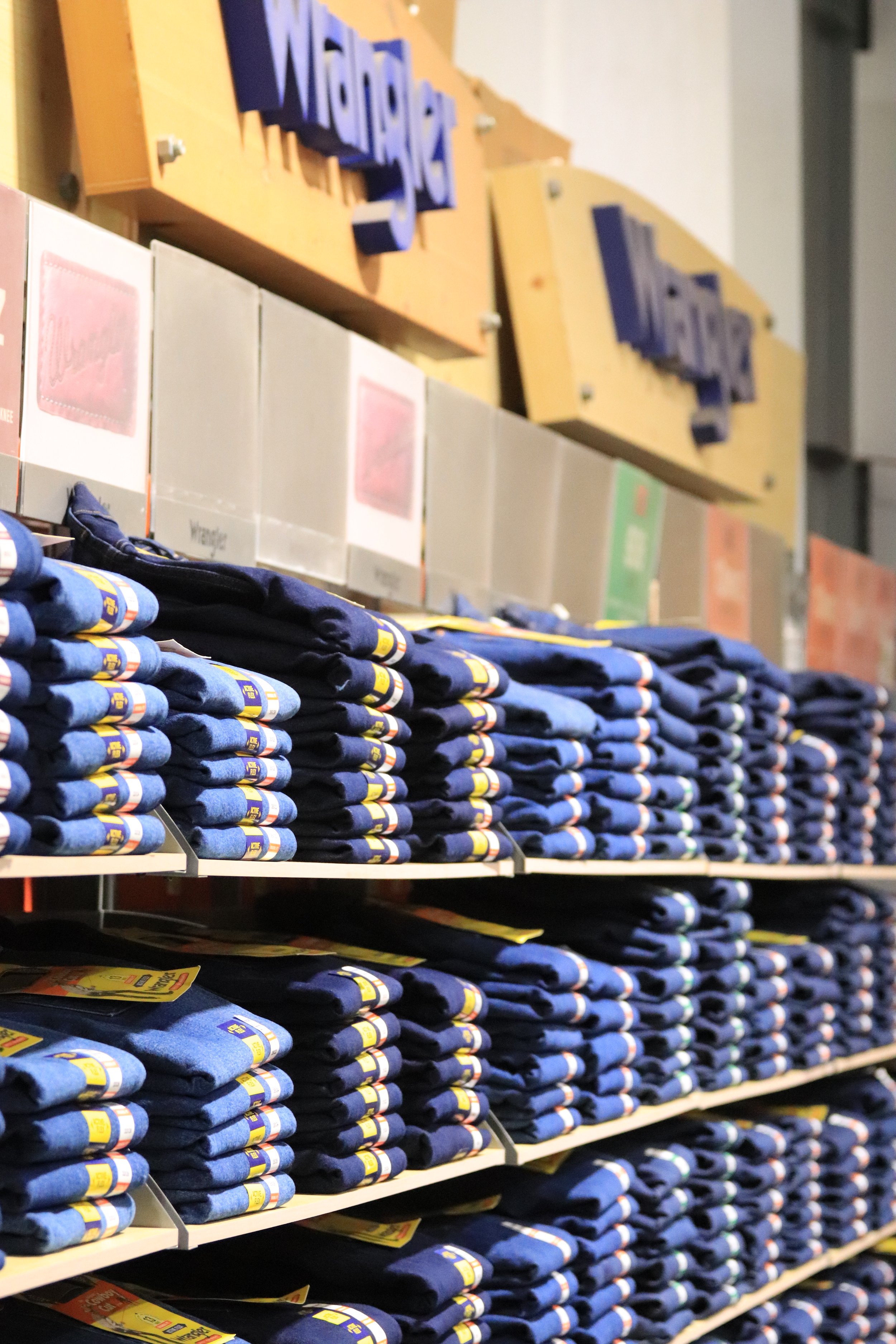 Stacked shelves of blue and black IKEA T-shirts inside a Walmart store.