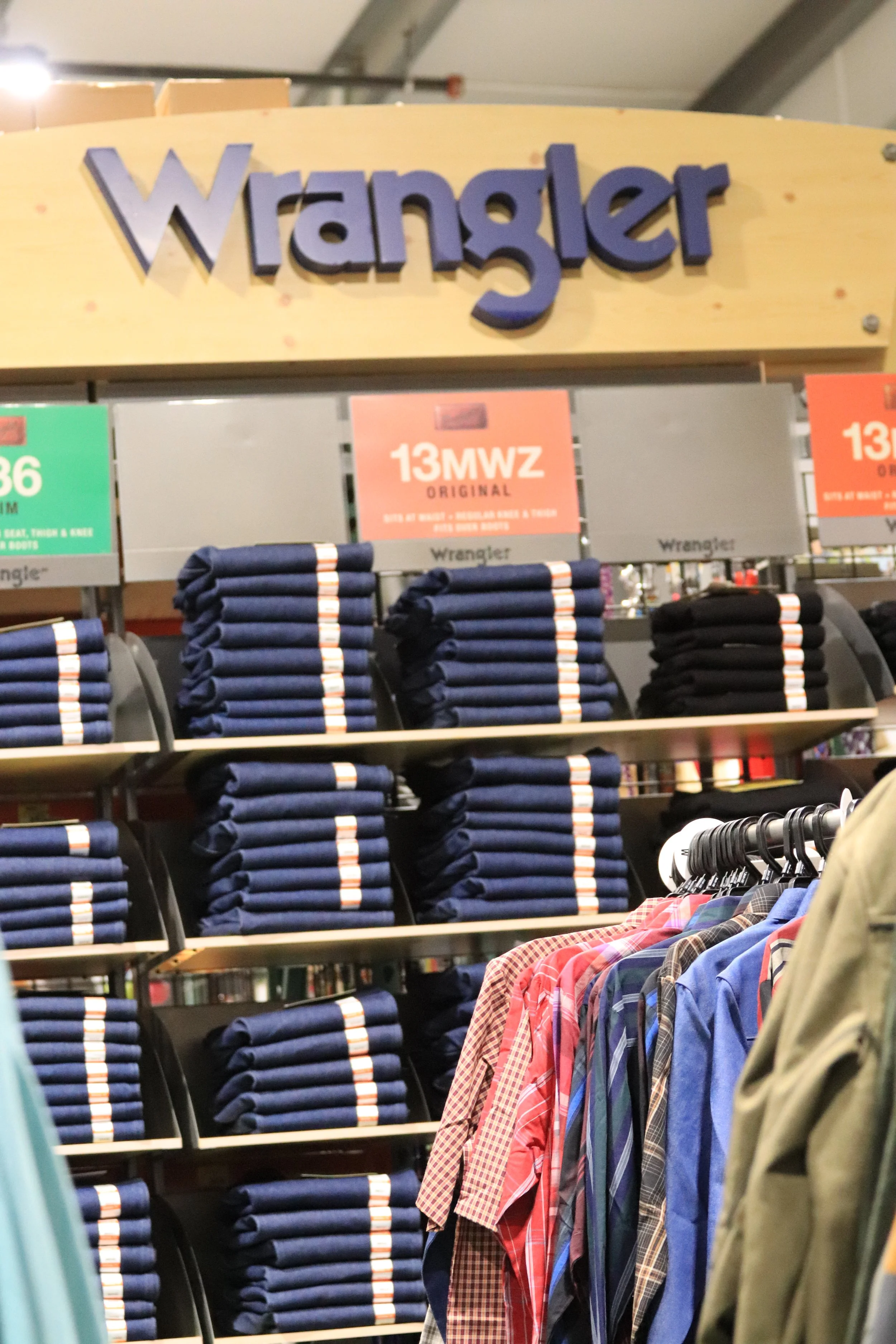 Display of stacks of Wrangler jeans and men's shirts at a retail store.