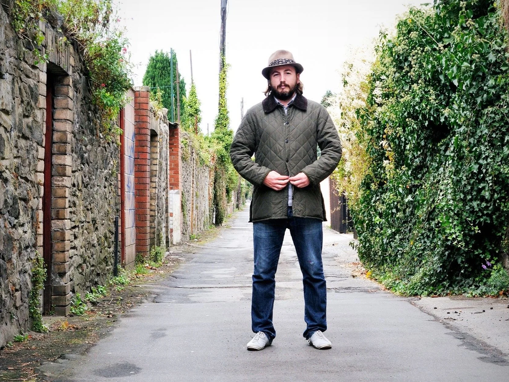 Man wearing quilted jacket and hat in alley