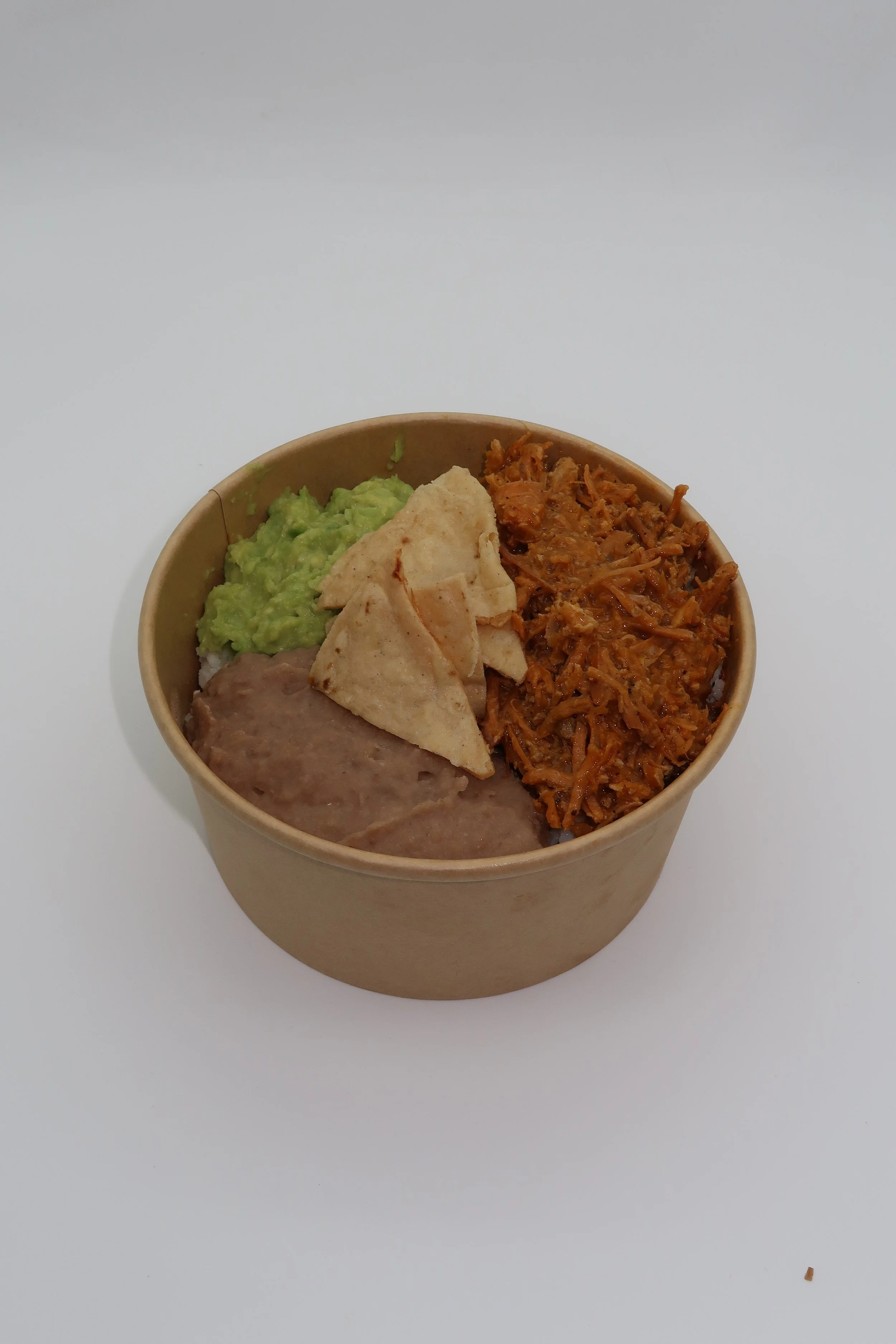 Tazón con frijoles refritos, guacamole, carne deshebrada y totopos.