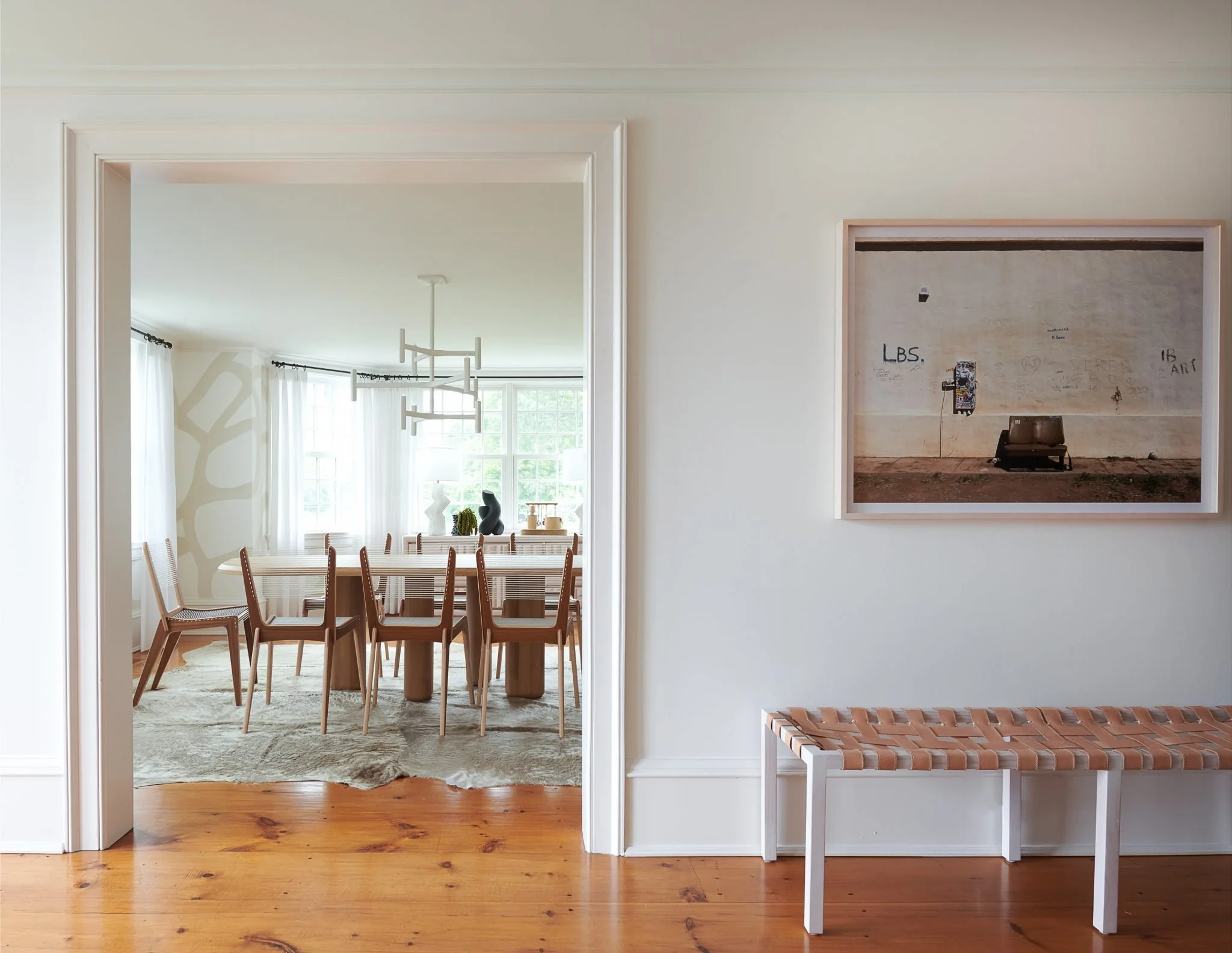 Dining room with warm tan tones alongside an entry area featuring a leather bench, showcasing layered textures and inviting design by Good Bones Design