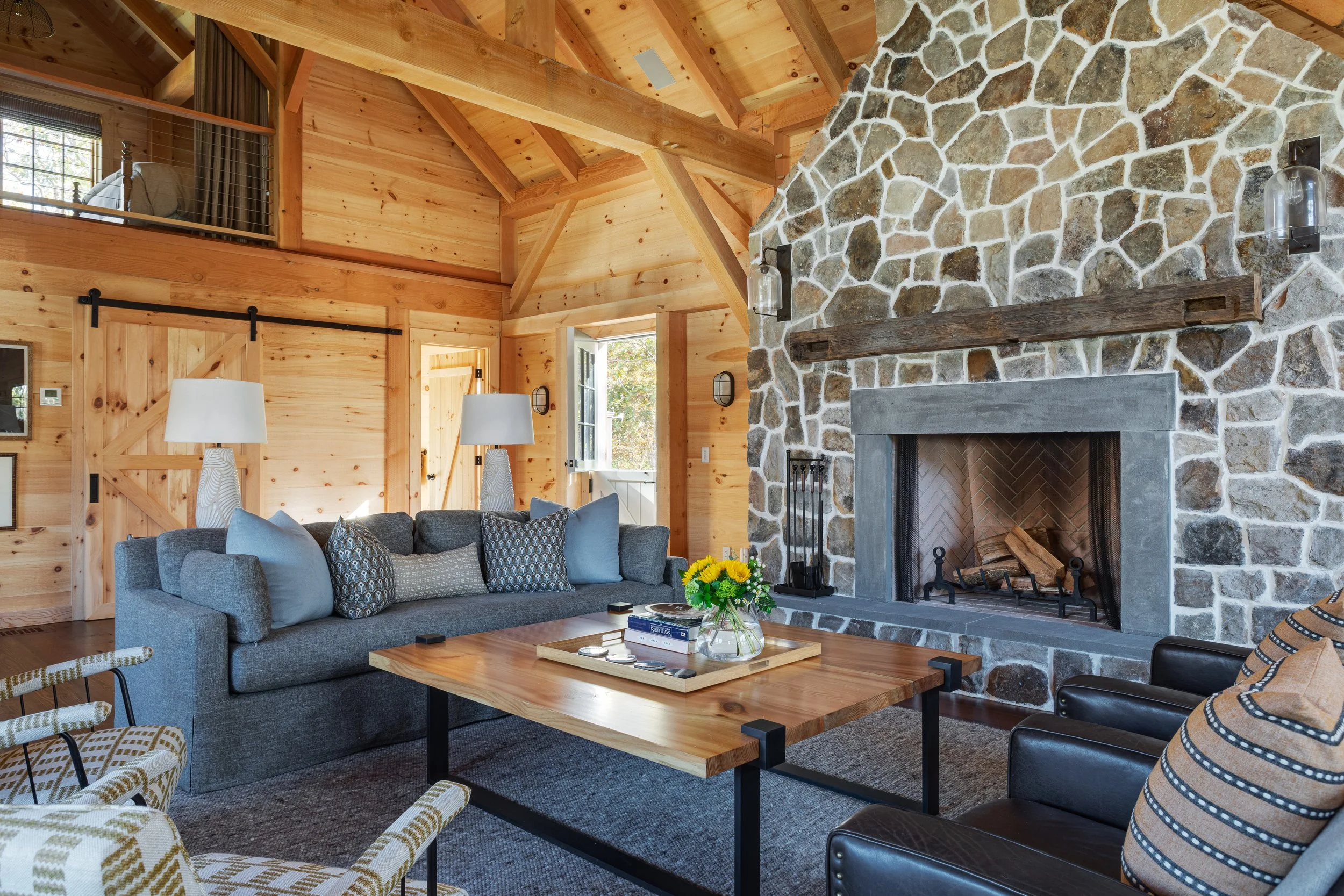 Family room interior by Good Bones Design with warm wood, a lot of light, stone fireplace and blue, gray and tan accents