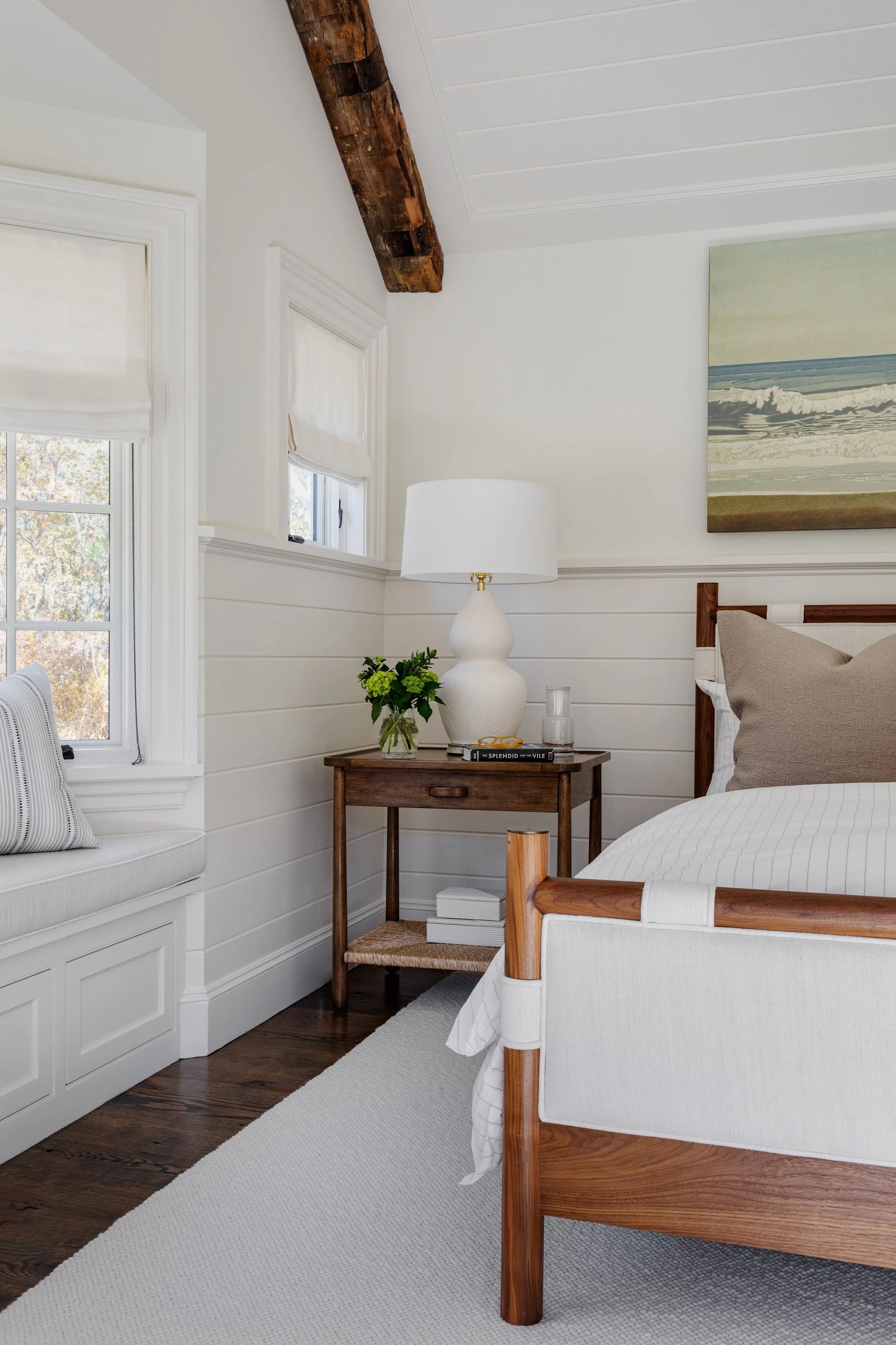 Bedroom interior by Good Bones Design with warm wood accents and coastal artwork