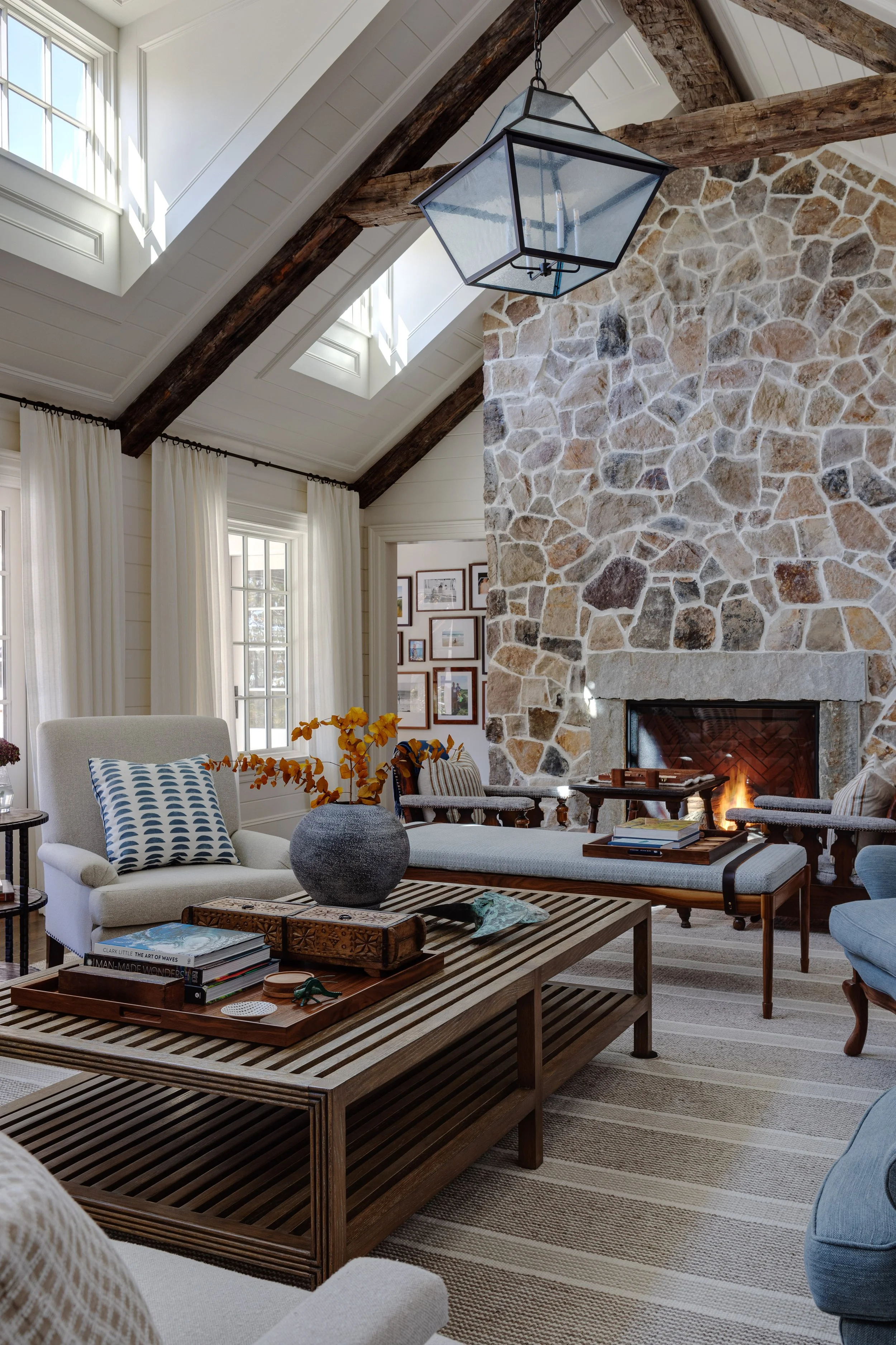 Living room interior by Good Bones Design with statement stone fireplace, warm wood accents and a blue and white color scheme