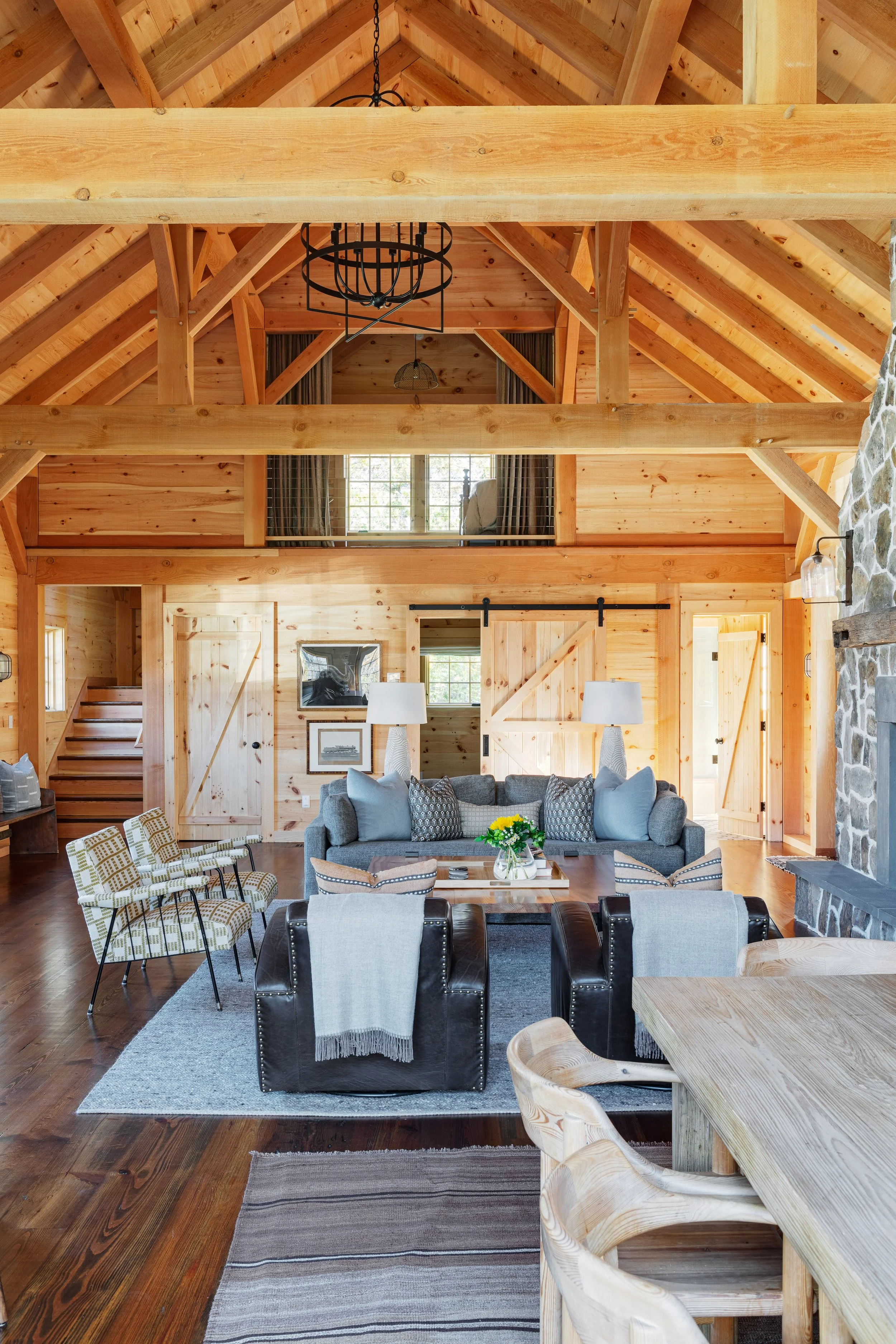 Kitchen into family room interior by Good Bones Design with warm wood, a lot of light, stone fireplace and blue, gray and tan accents